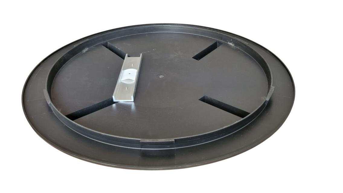 Black circular plastic lid with a metal handle in the center, featuring four indented sections around the edge.