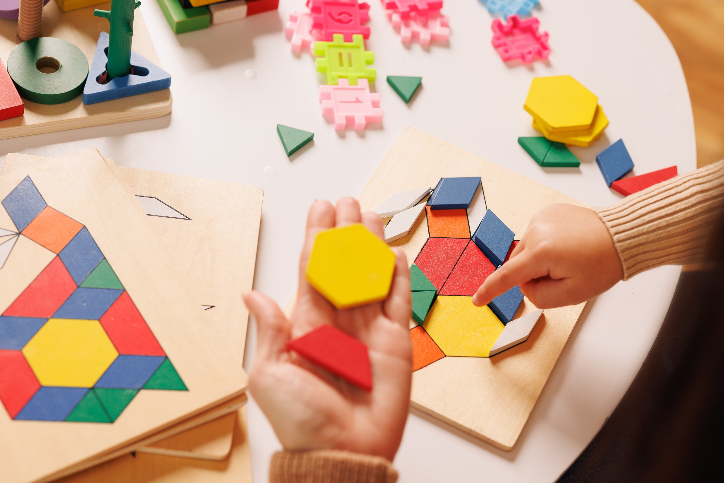 Child and parent playing with a colorful wooden educational toy, improving motor skills and learning shapes through hands-on interaction