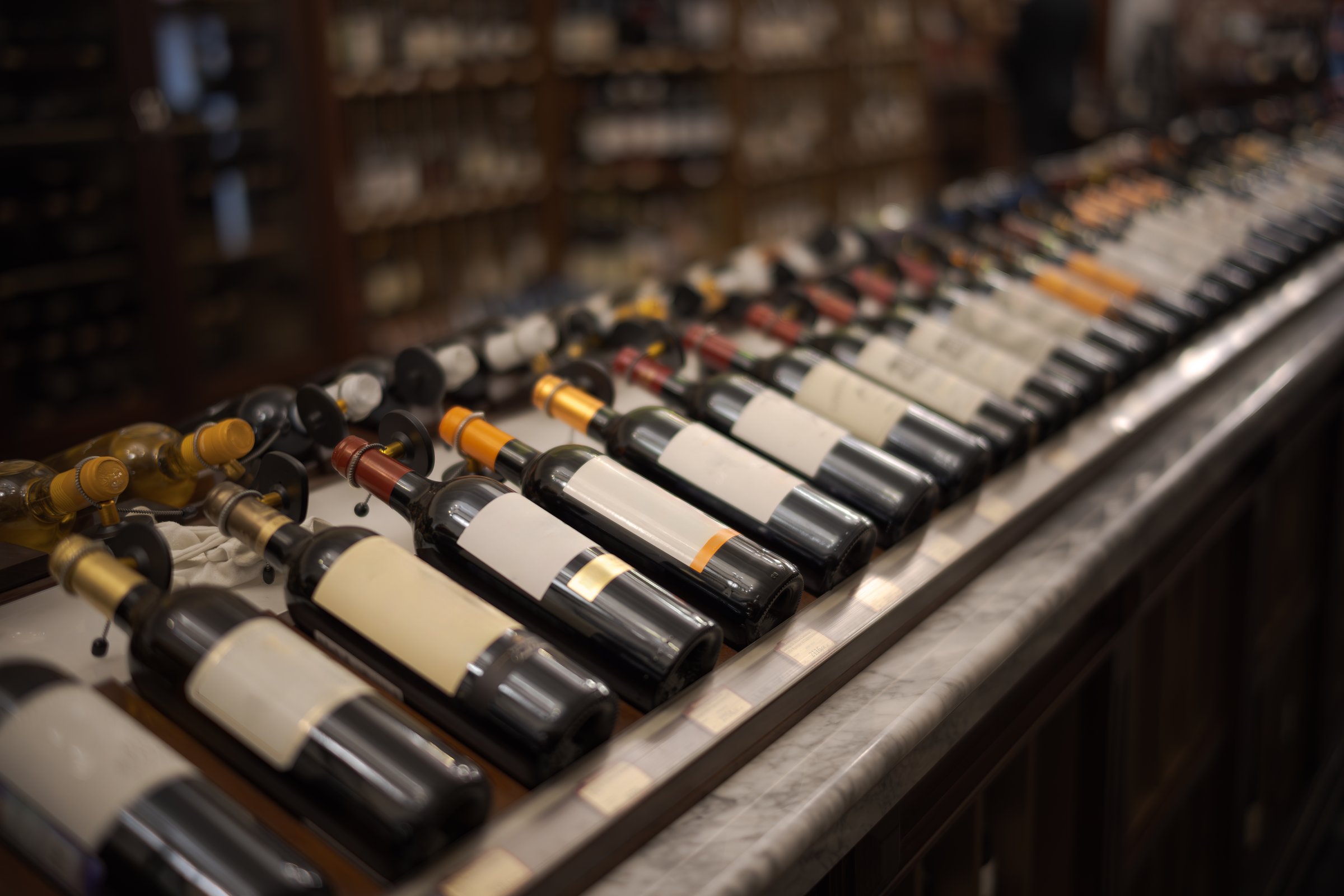 Row of wine bottles with dry red and white wine on wooden. Low depth of field. Winemaking and wine shop concept