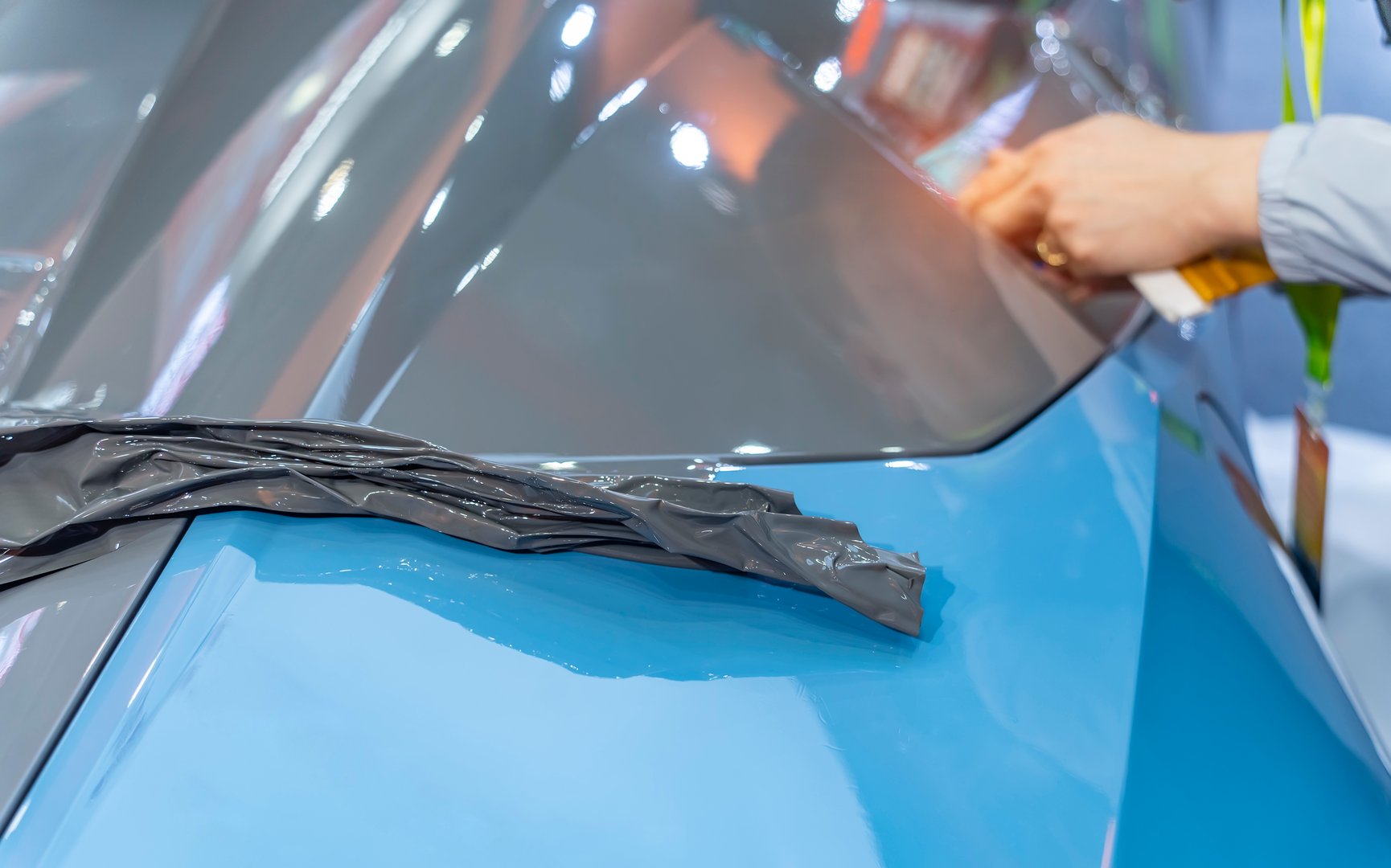 Worker install car paint protection film with spatula