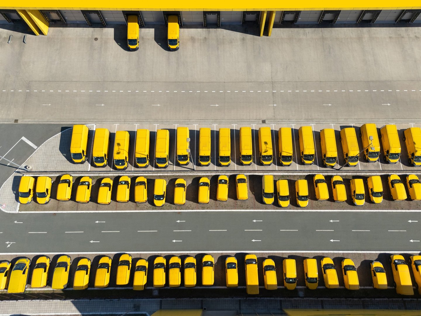 Drone point of view of delivery vans hub. Fleet of yellow post vehicles.