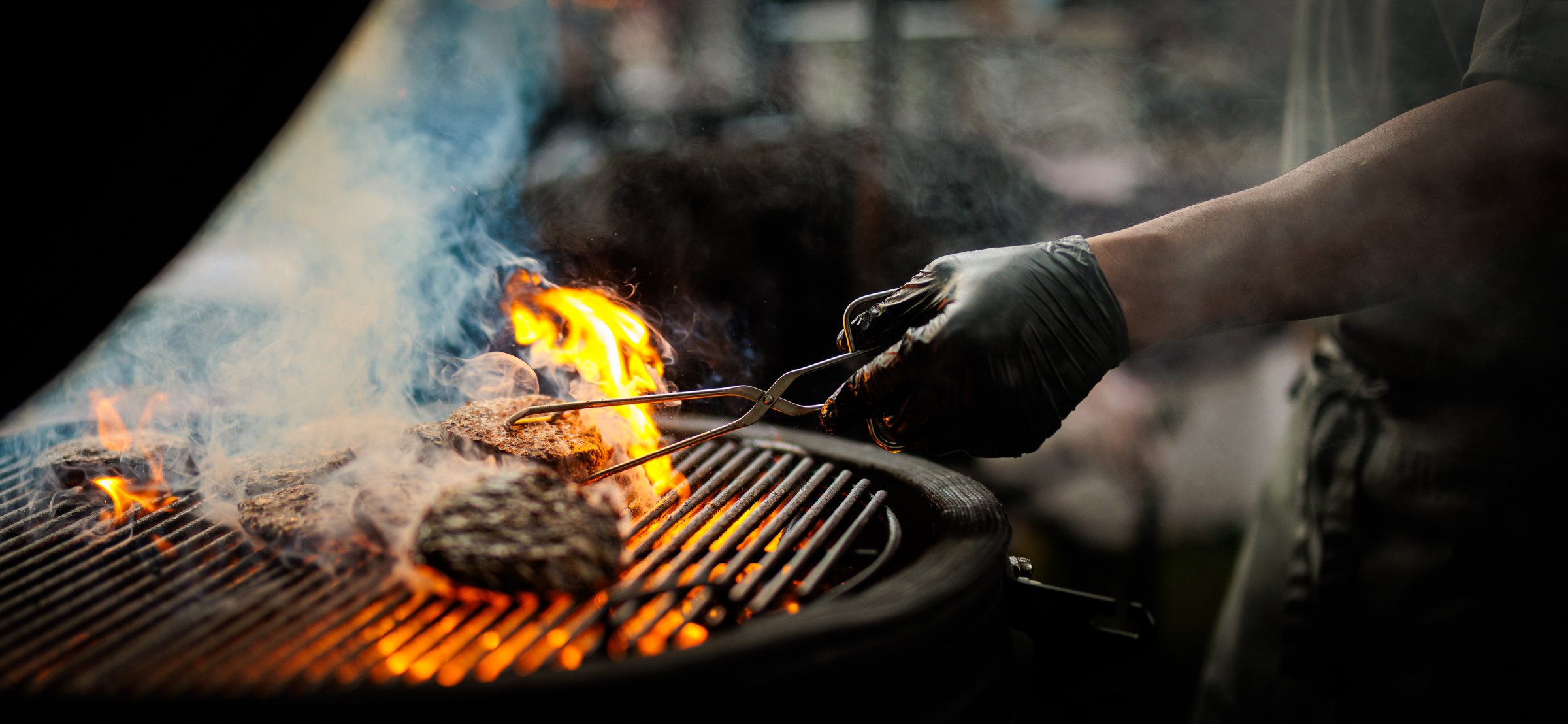 A shef turning a burger on a barbecue