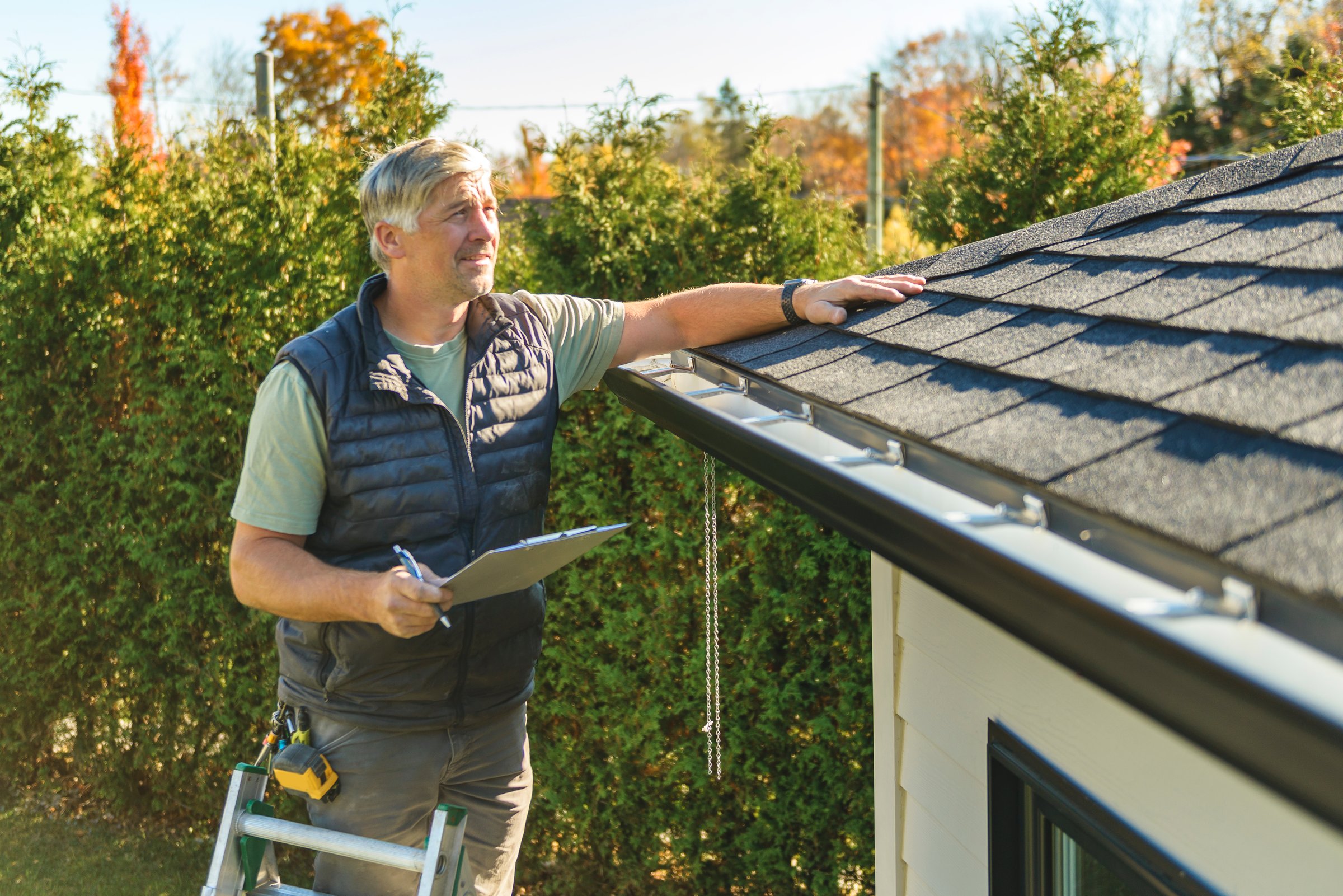 A man standing on steps inspecting house roof