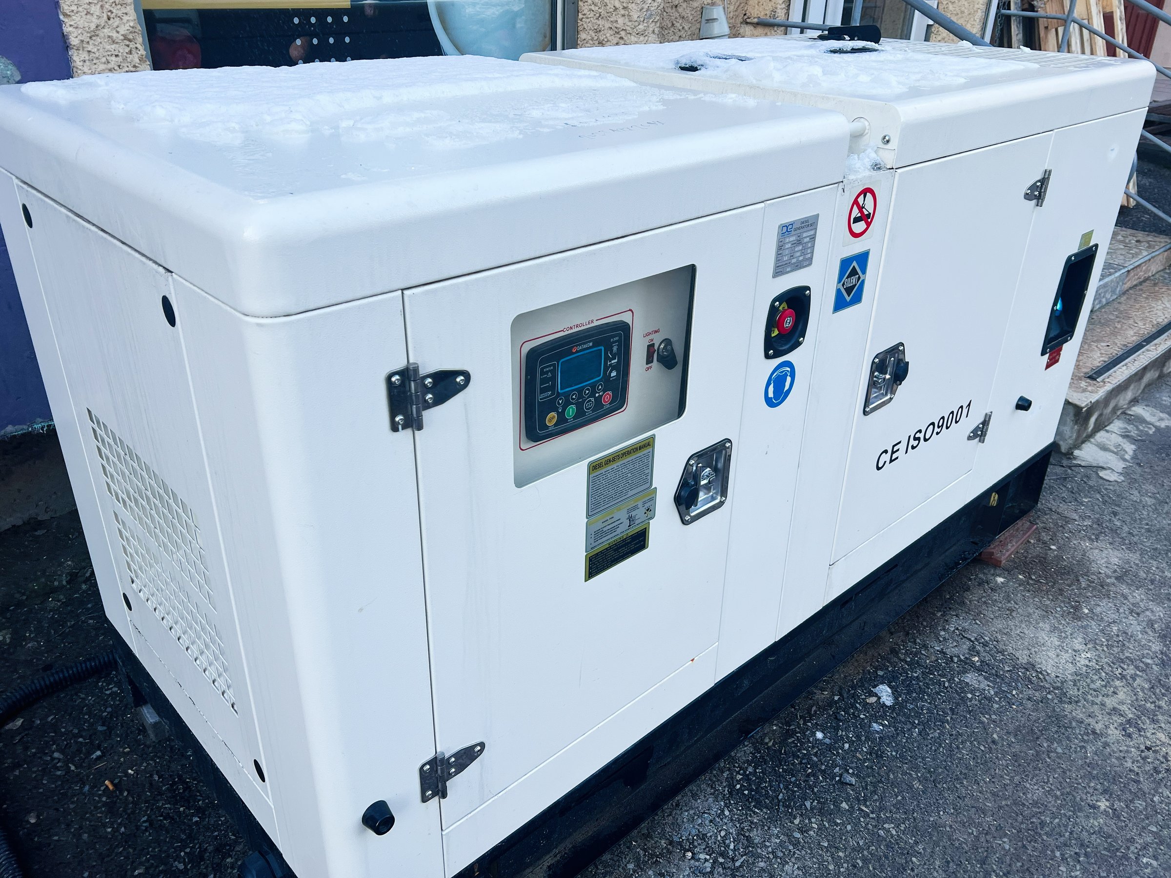 Kyiv, Ukraine - January 11, 2025: A modern white generator unit situated outside in a winter setting. The equipment features functional controls and safety labels, highlighting its heavy-duty and industrial application in energy supply.