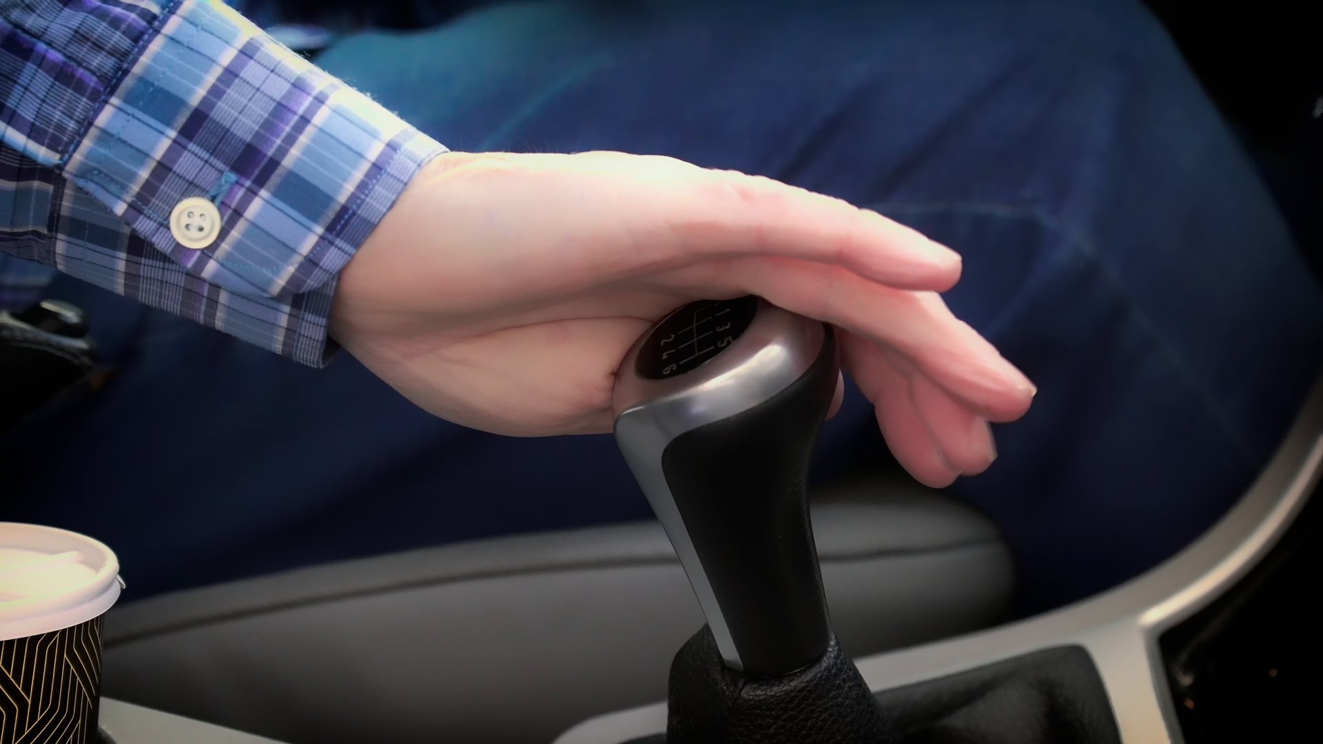 Close-up of a driver's hand shifting gears in a car with a manual transmission