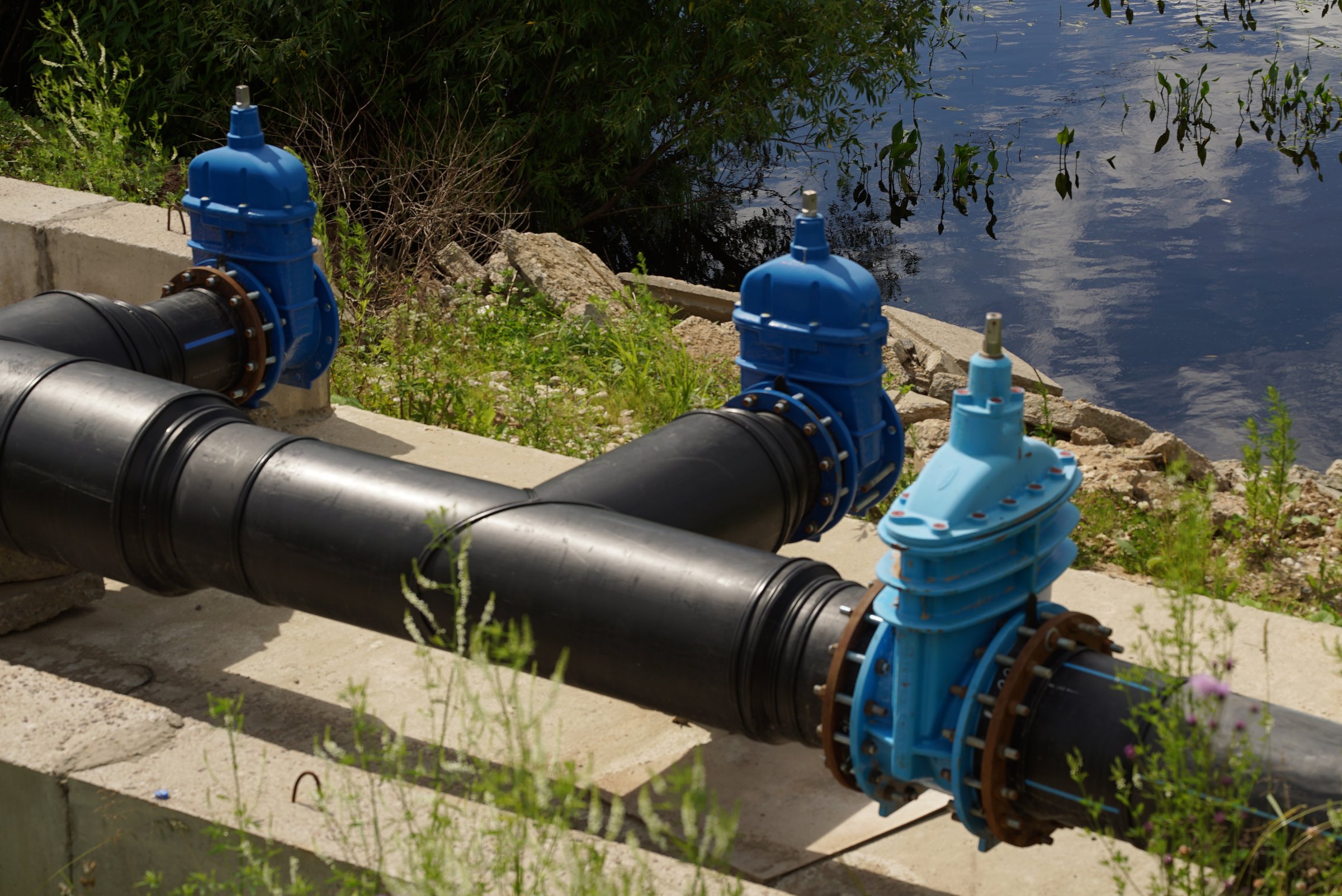 Industrial Water Supply Pipelines Featuring Valves and Advanced Control Mechanisms. Pipelines and valves play a crucial role in the water supply systems located near a river, ensuring efficiency.