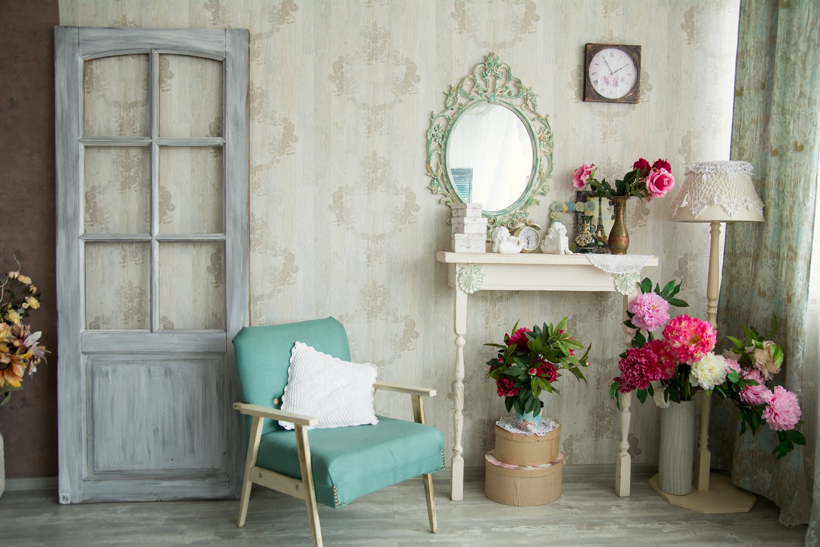 Vintage country house interior with mirror and a table with a vase and flovers. Interior design with a door and an old chair.