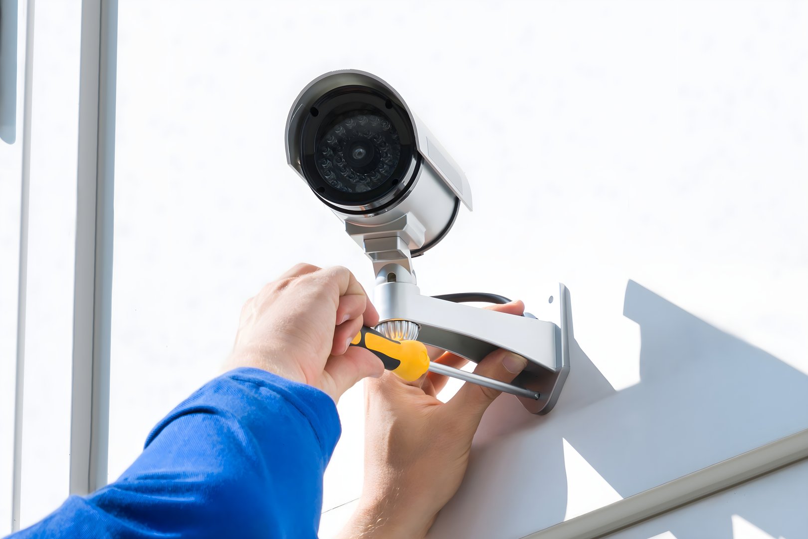 Technician Fixing Camera On Wall With Screwdriver