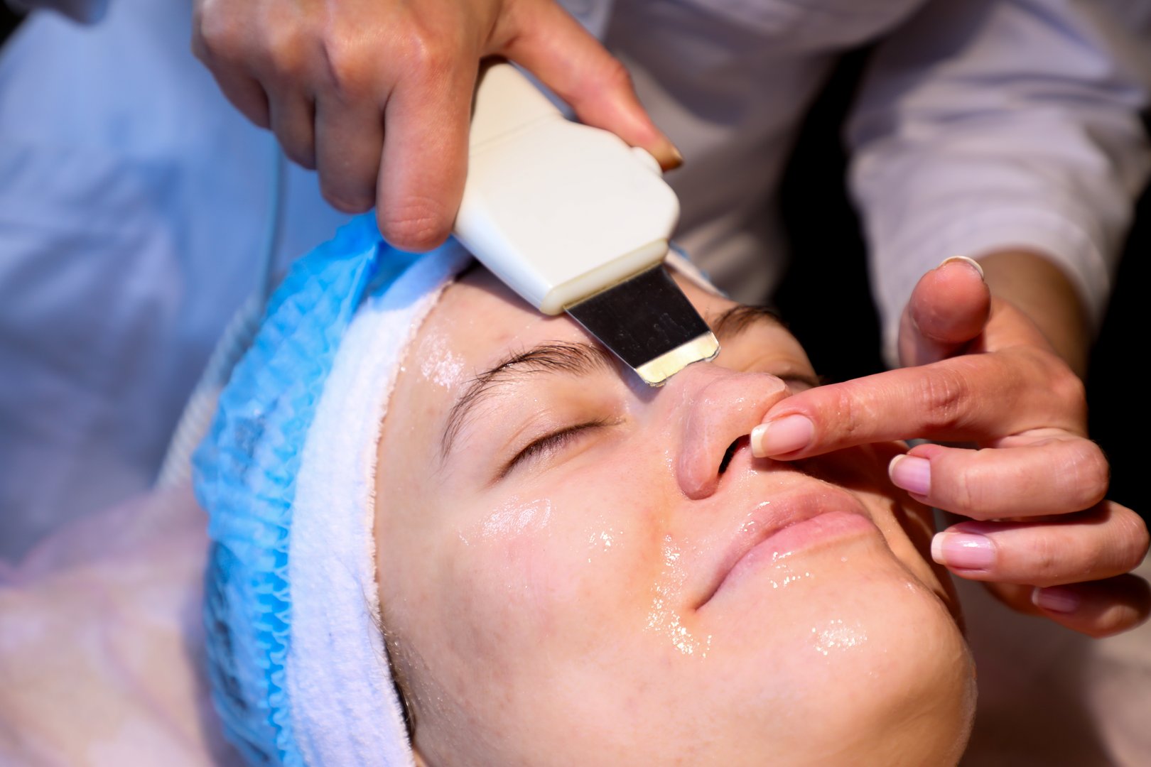 Using an ultrasonic scrubber, a cosmetologist performs a procedure for a young woman (from the series "cosmetology room").