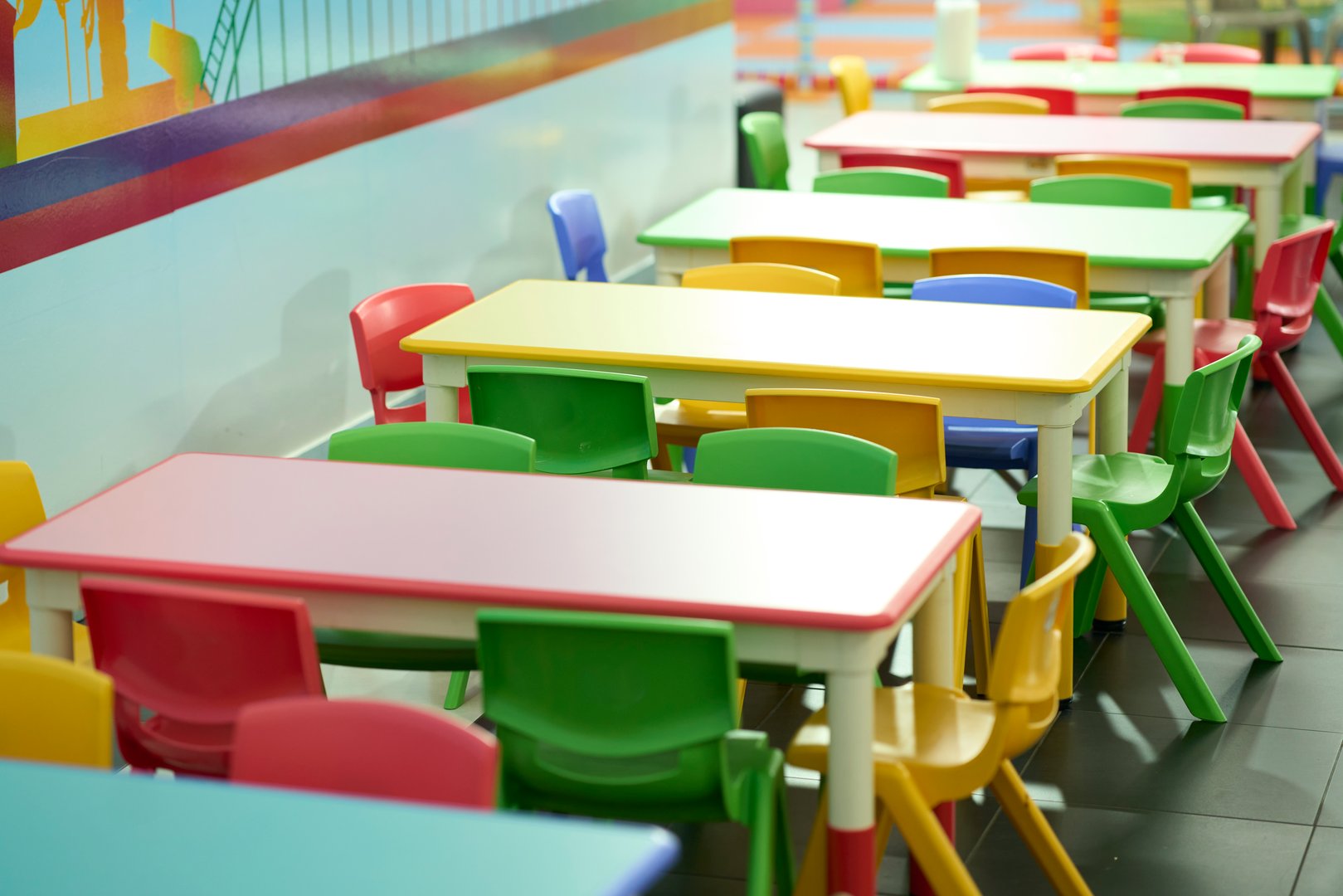 Colorful children's tables and chairs in a vibrant classroom setting.