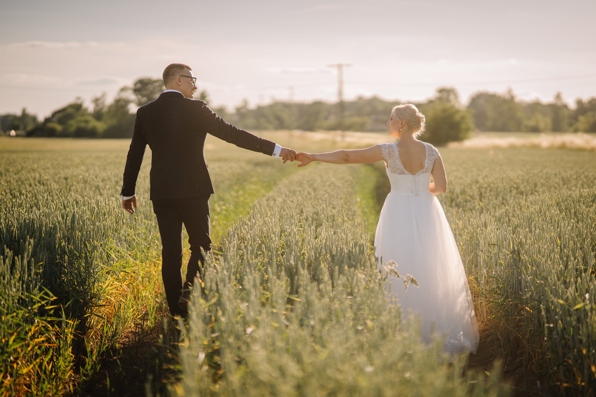 Bride and groom stroll together in a golden wheat field, surrounded by nature, embodying joy and connection in a beautiful outdoor wedding scene