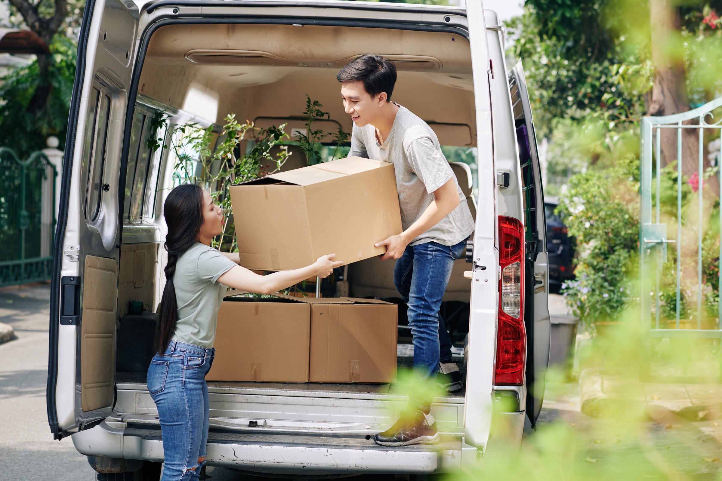 Professional movers carefully loading moving truck, team working together to transport furniture and boxes