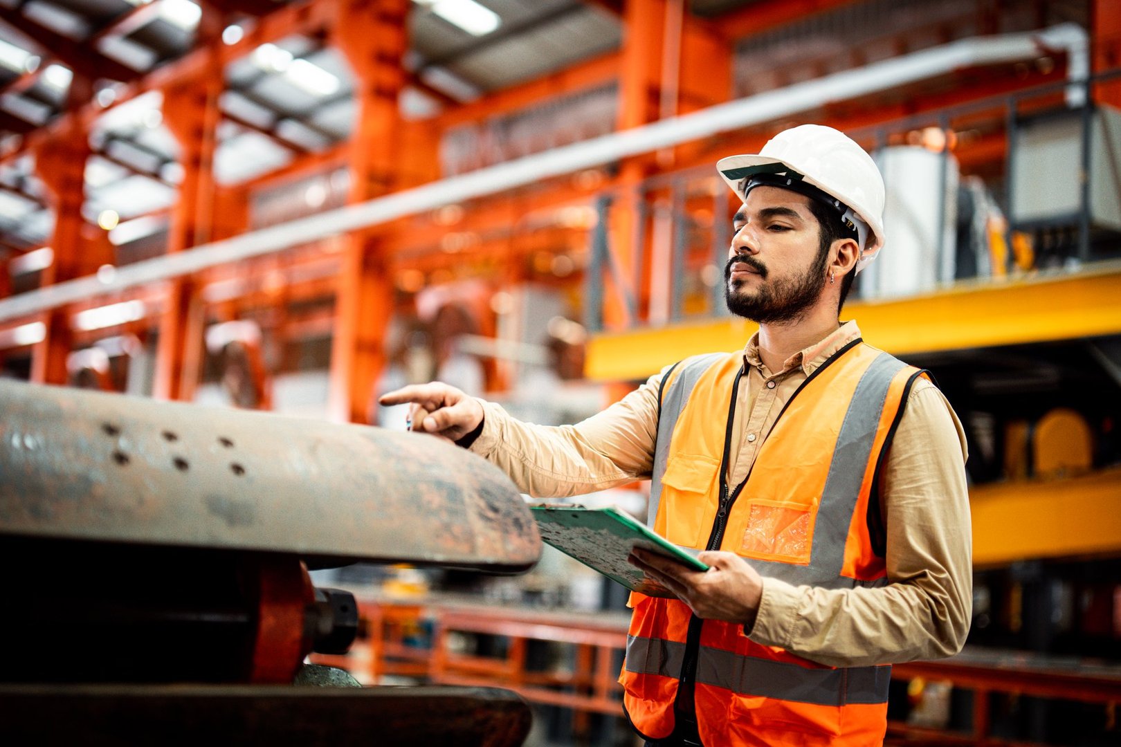Men industrial engineer wearing a white helmet while standing in a heavy industrial factory behind. The Maintenance looking of working at industrial machinery and check security system setup in fact