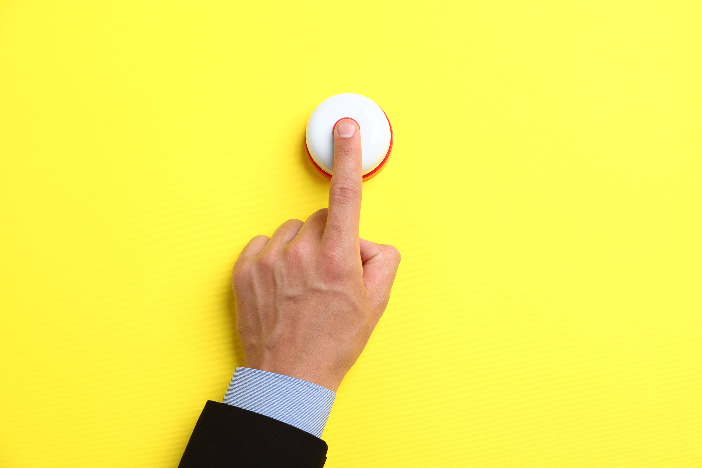 Man pressing button on yellow background, top view. Space for text