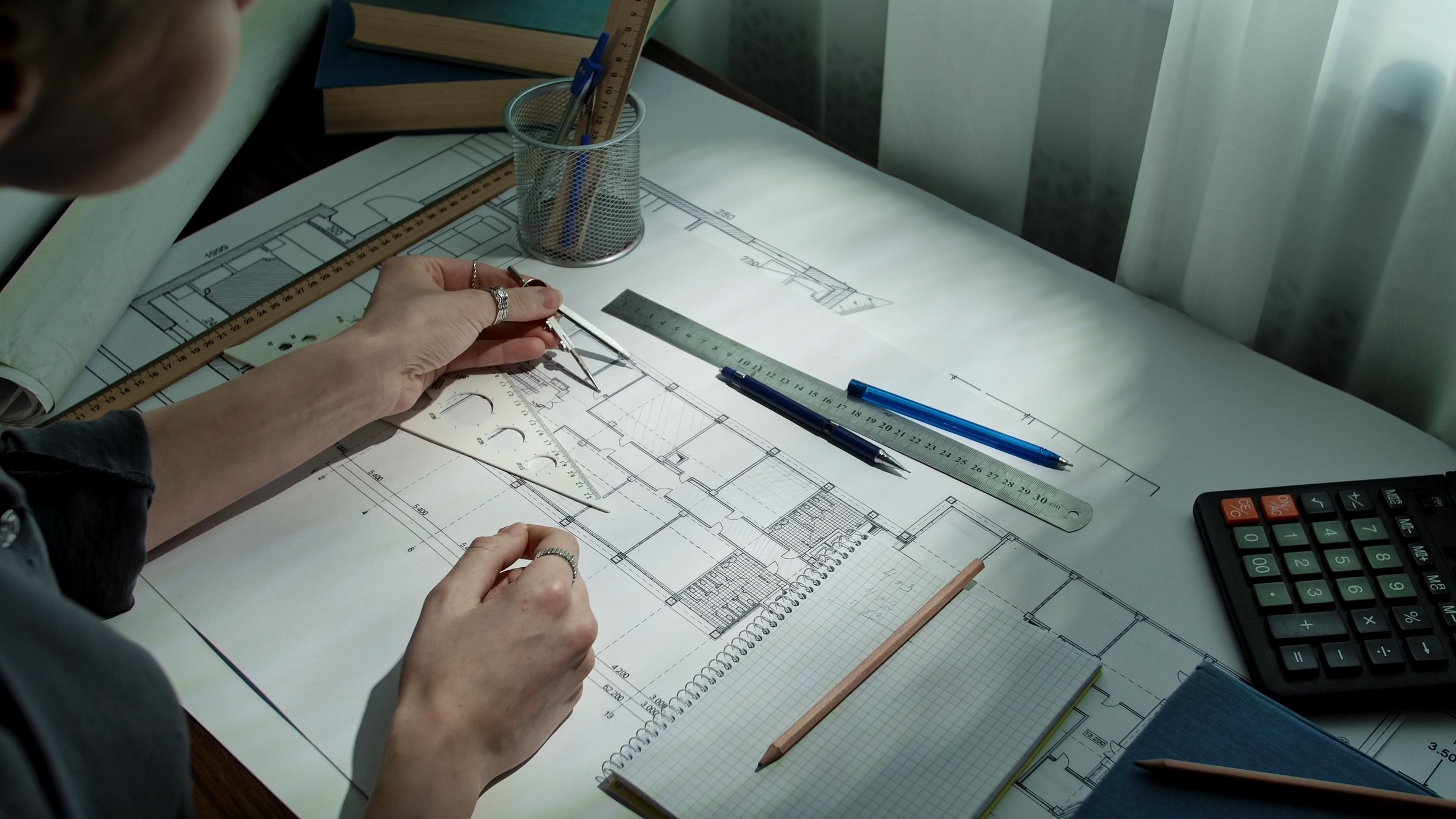 An architects workspace showing blueprints, drafting tools, and a calculator, emphasizing precision in design.