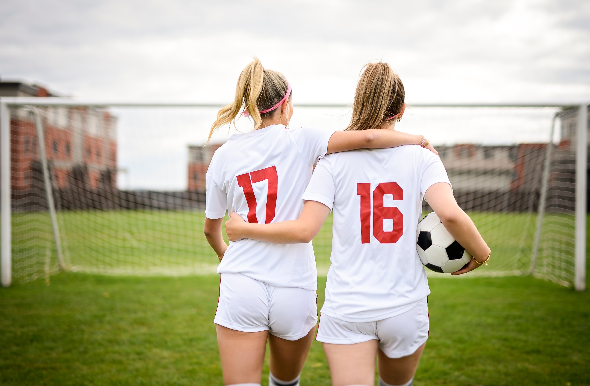 The two soccer player friends with a football in a sport uniform wearing in white