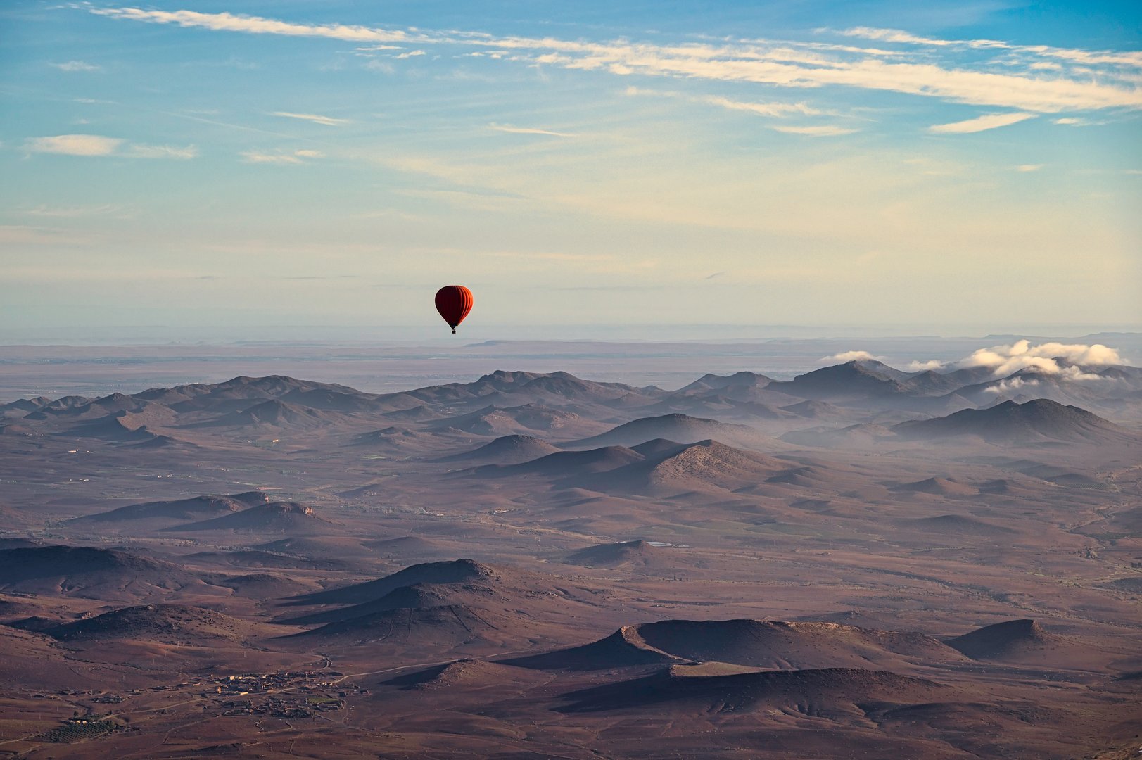 A red, hot air balloon, floating over the desert near Marrakech, Morocco on a clear spring day