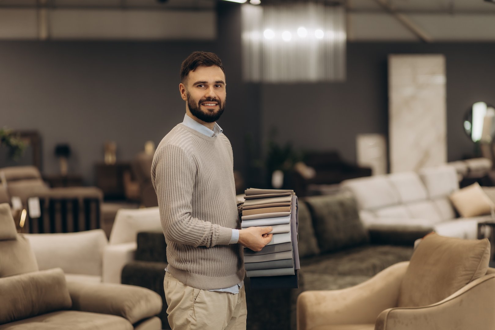 Confident salesman standing in furniture store exhibition center.