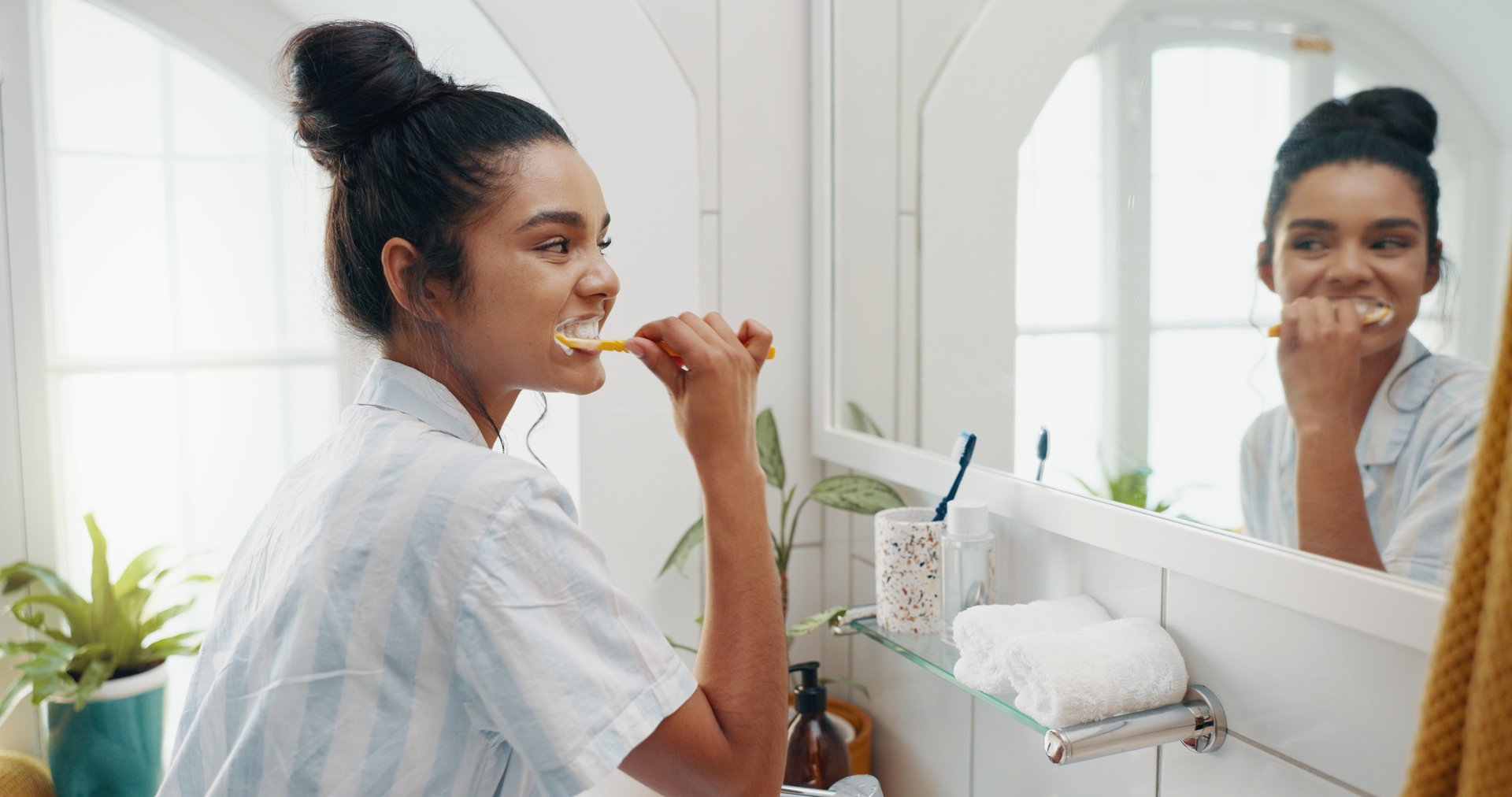 Mirror, home and woman brushing teeth, grooming and hygiene with morning routine. Person, reflection and girl with toothbrush, fresh breath and cleaning mouth with wellness and whitening in bathroom