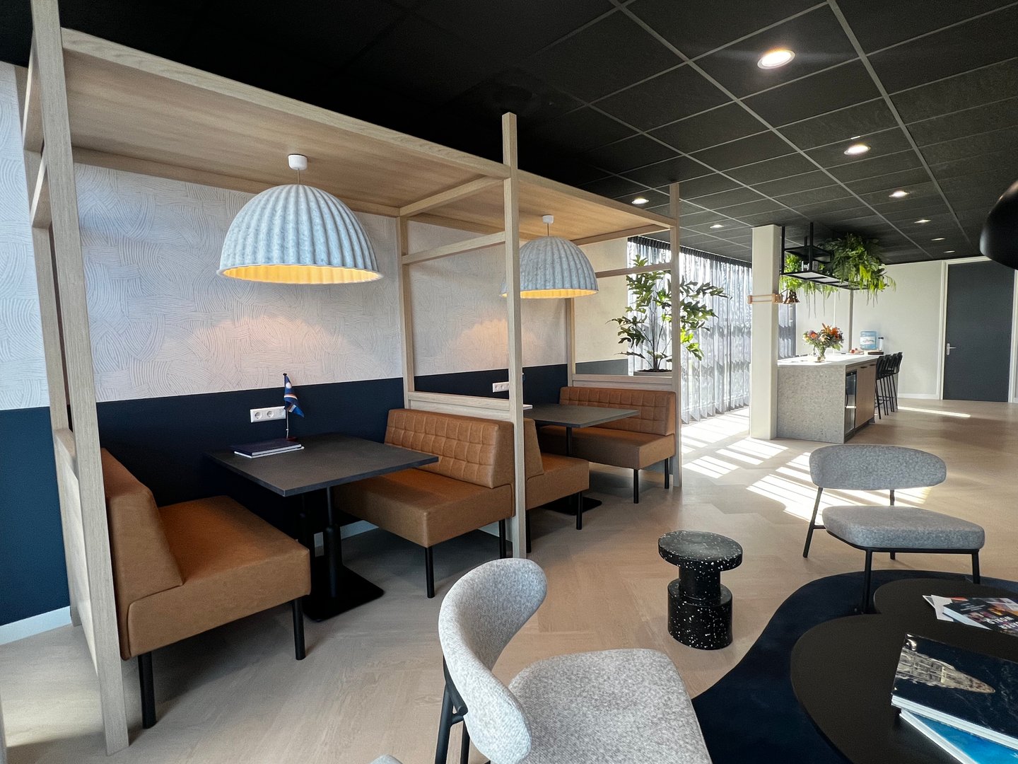 Modern cafe interior with leather booths, hanging lamps, and contemporary seating arrangements.