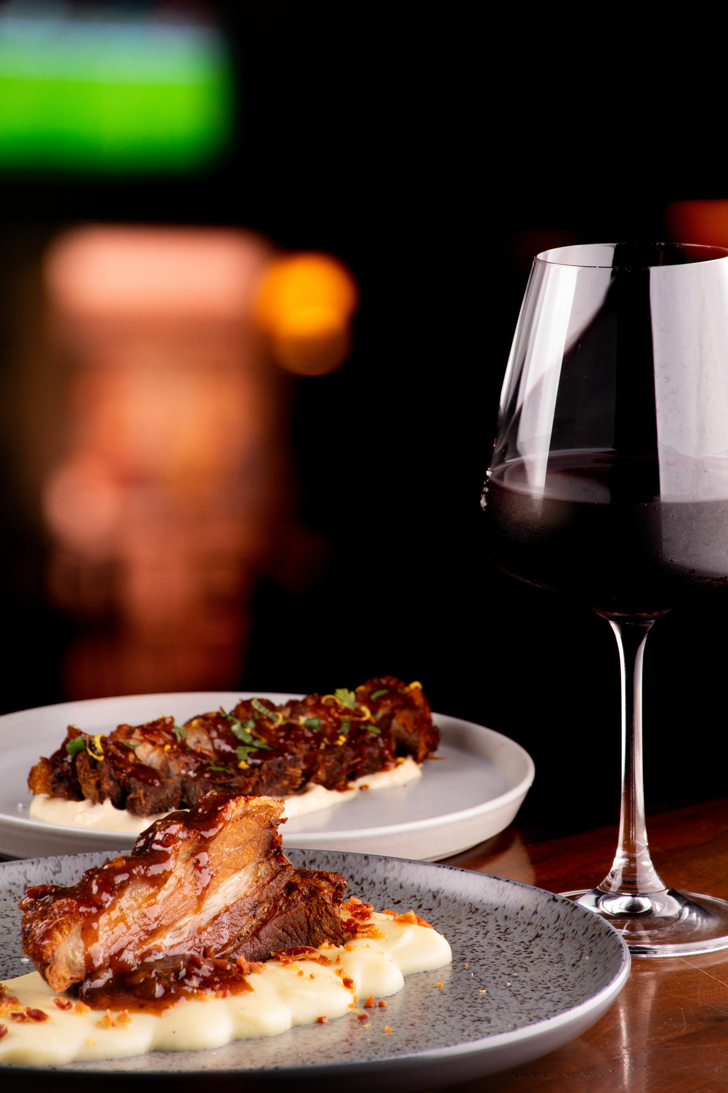 close-up of a piece of pork belly on a bed of parmesan cheese paired with red wine