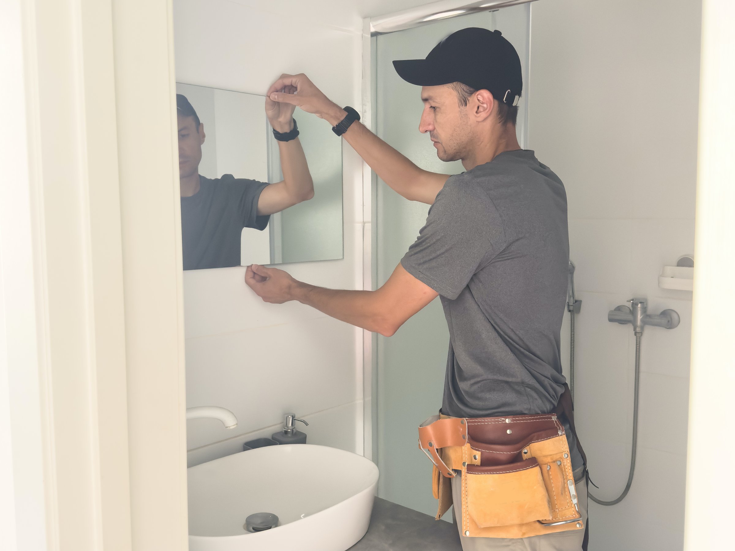 Handyman installing a mirror in bathroom. High quality photo