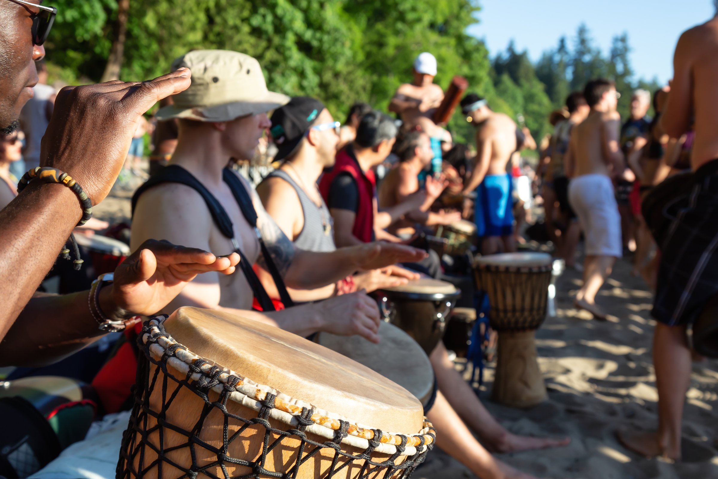 Third Beach, Downtown Vancouver, British Columbia, Canada - May 22, 2018: Crowd of People are having fun and celebrating at a Drum Circle Event during a vibrant sunset.