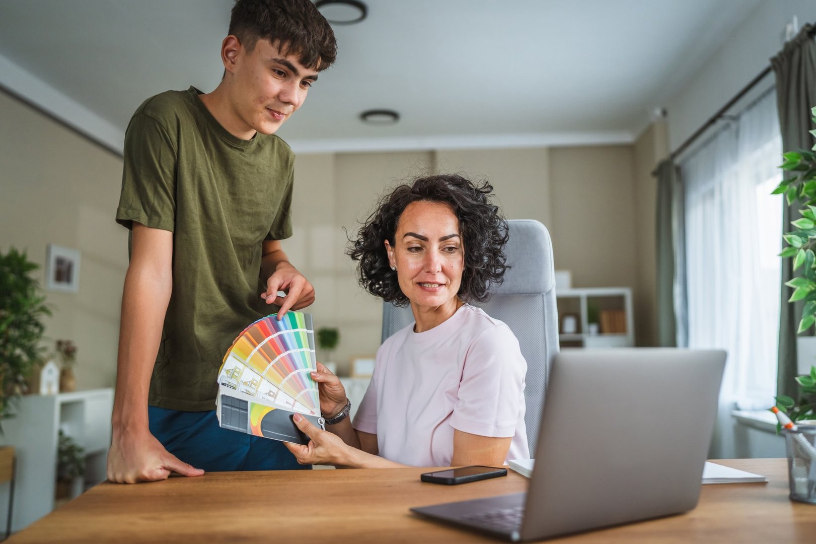 Teenage boy and mother showing color palette on video call with interior designer
