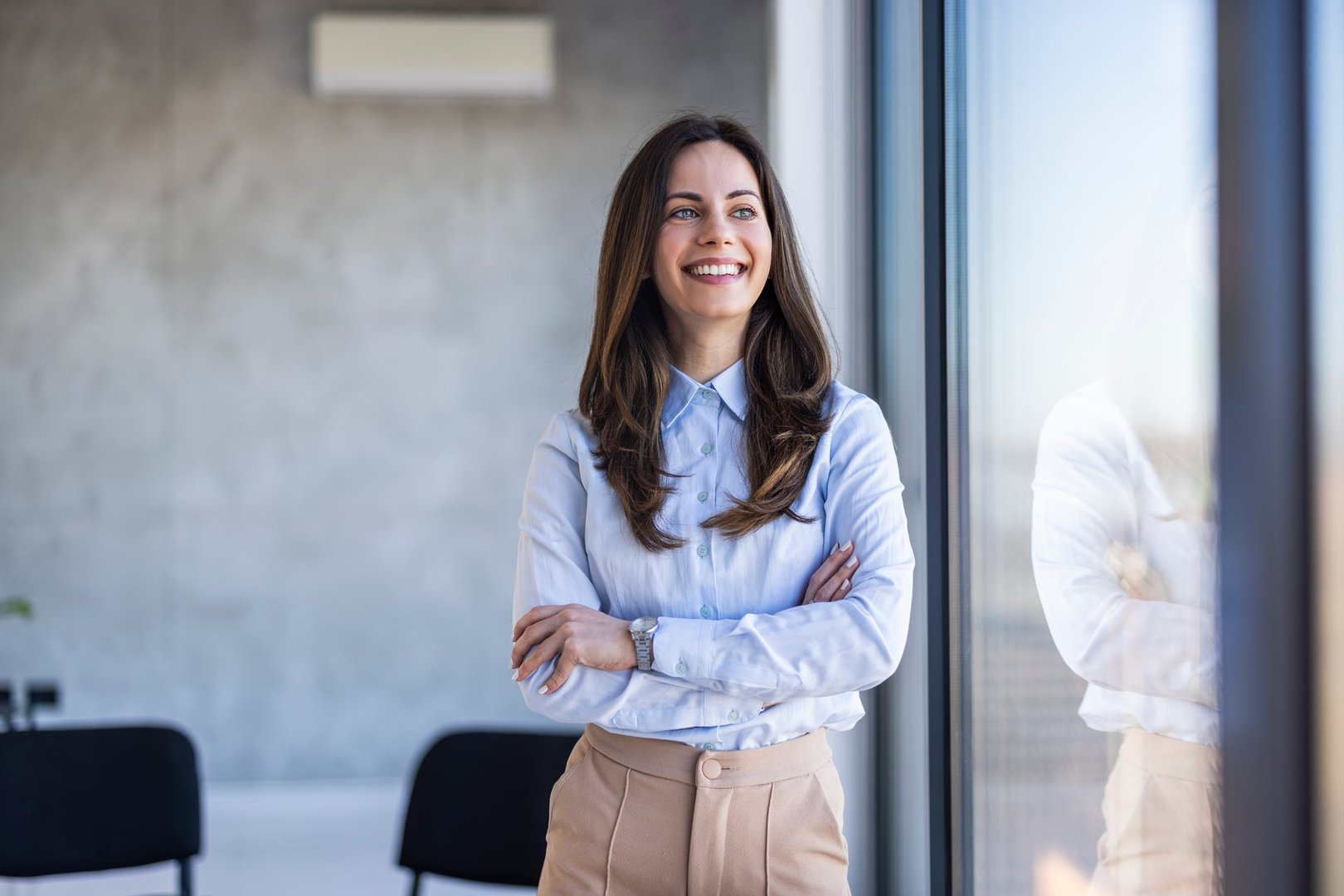Waist up portrait modern business woman in the office with copy space. Female executive wearing businesswear standing outside modern meeting room. Portrait of a businesswoman standing in the office