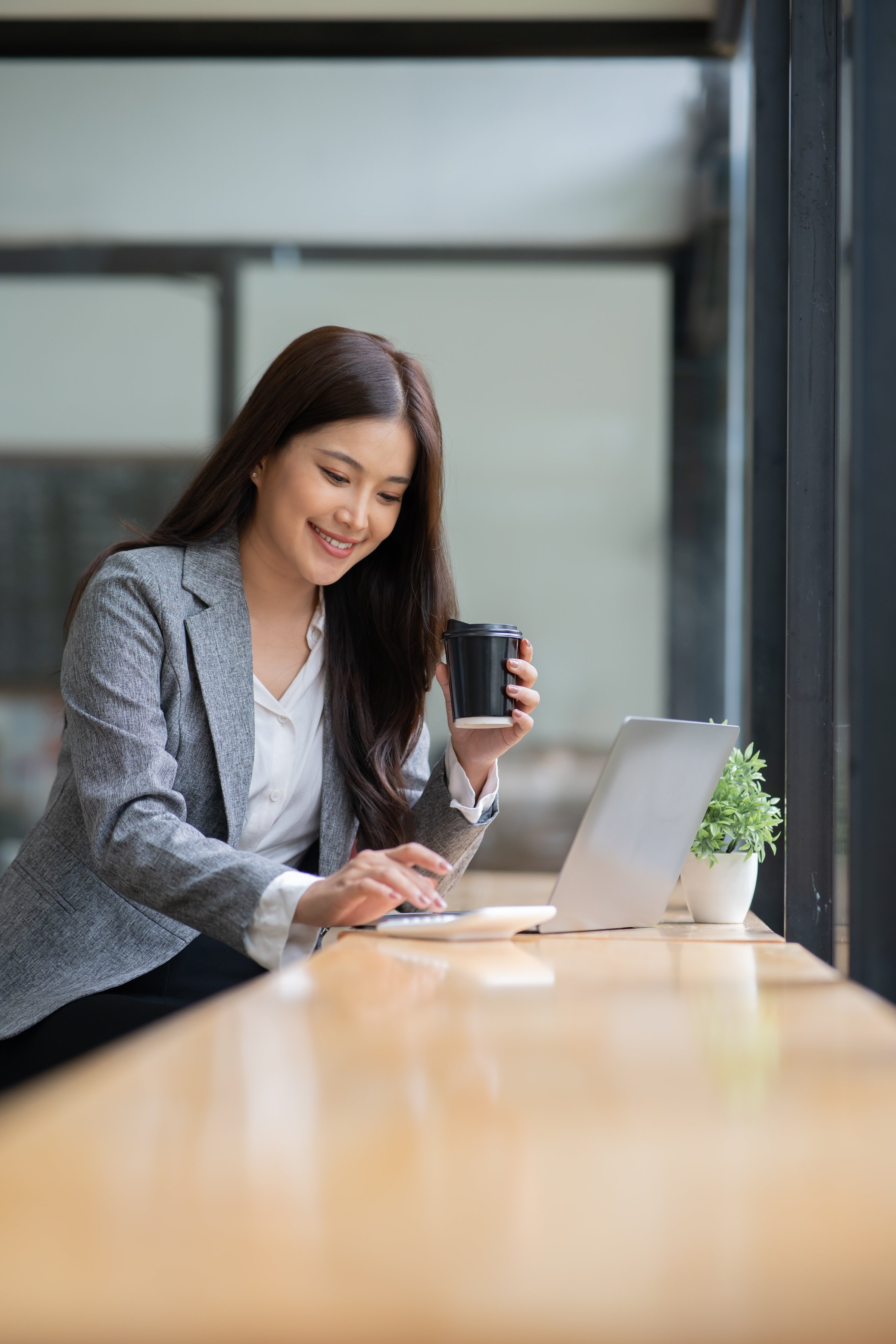 Asian businesswoman using tablet, chatting at bar, coffee shop