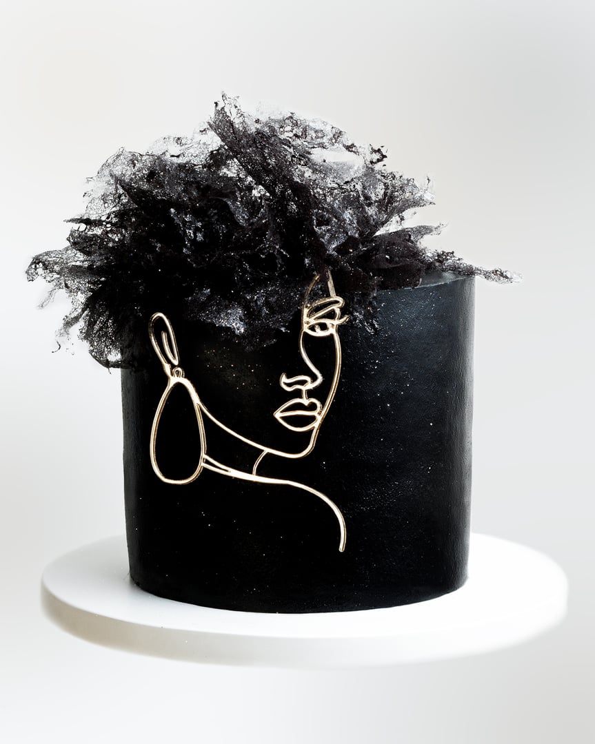 a black cake with a girl's face and hair on top of the cake