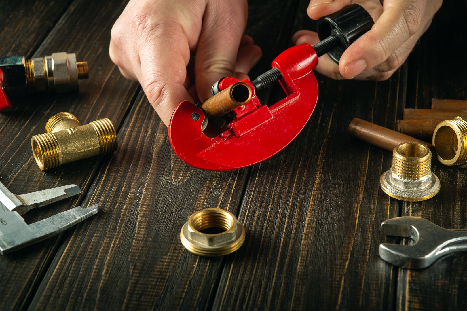 The plumber cuts a pipe with a pipe cutter to repair a gas line. Close-up of a master's hand while working in a workshop.