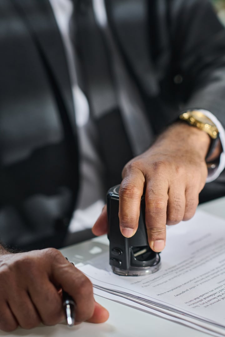 Hand of mature unrecognizable male lawyer or solicitor putting stamp on contract or other paper document after signing them