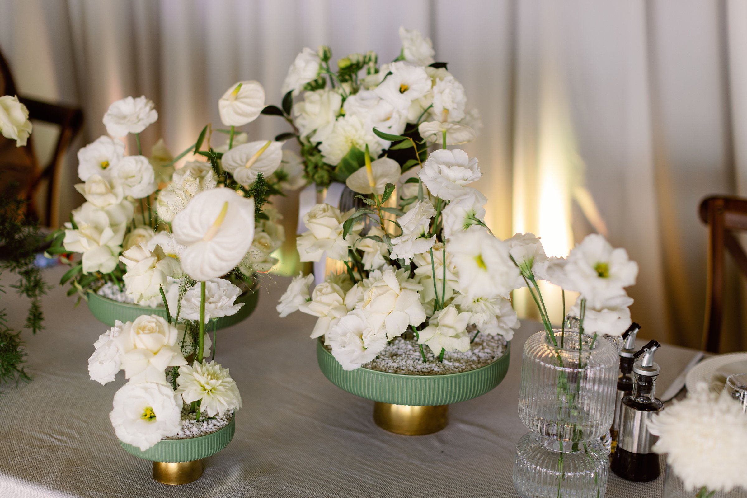 An elegant floral arrangements with white flowers in vases on a table in a wedding venue