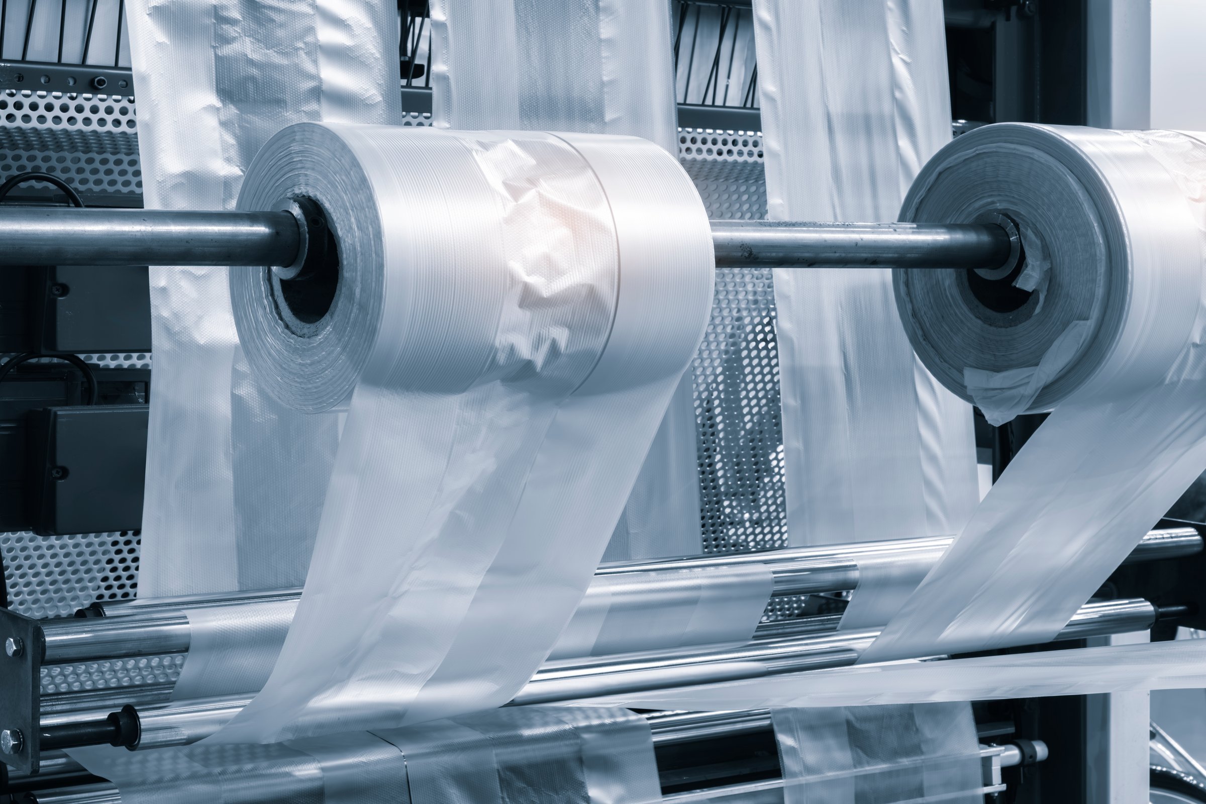 Automatic polyethylene plastic bag production machine with lighting effect. Close-up of the roller of the plastic bag production machine in the light blue scene. product packaging concept