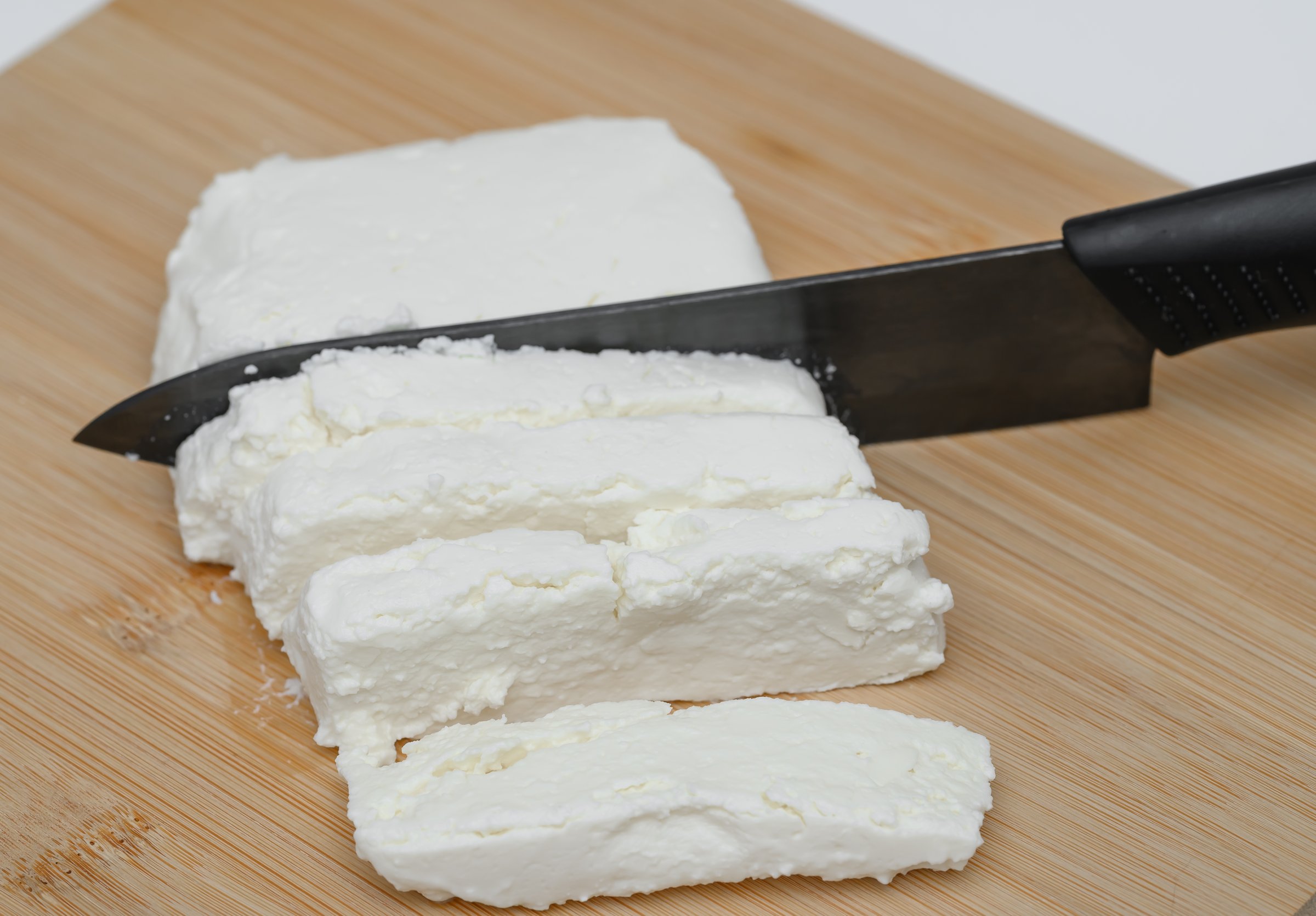 Cottage cheese in a box, sliced on a chopping board, close-up, calcium sources