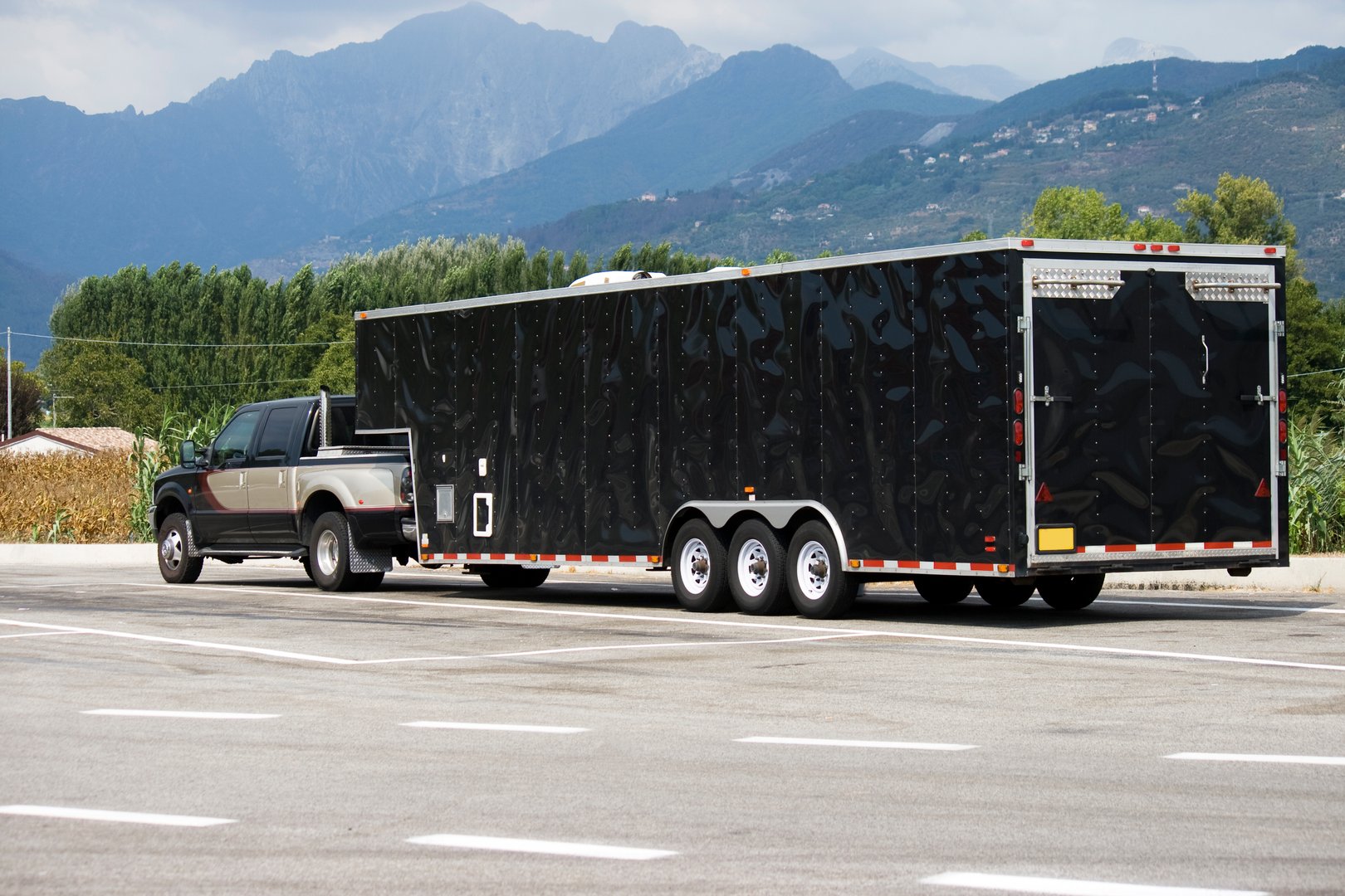 View of a SUV with a large black truck approaching an highway