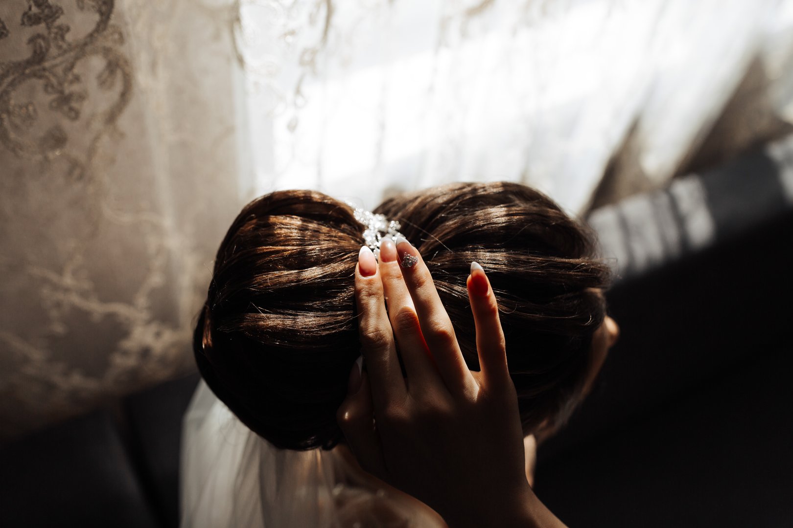 A woman with a bun on her head is touching her hair. Concept of intimacy and closeness between the woman and the viewer