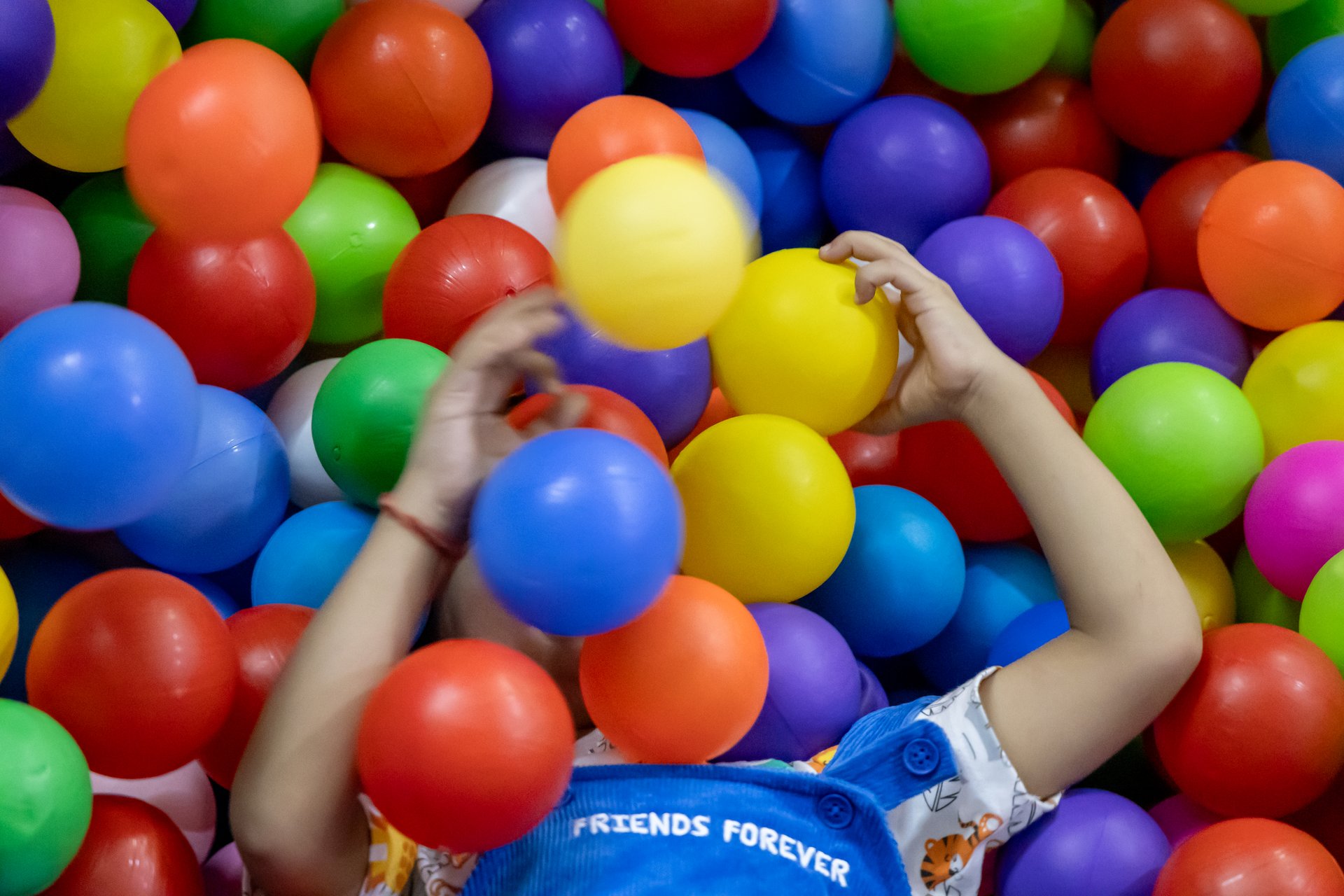 indian toddler boy face covered with colorful ball at indoor play zone