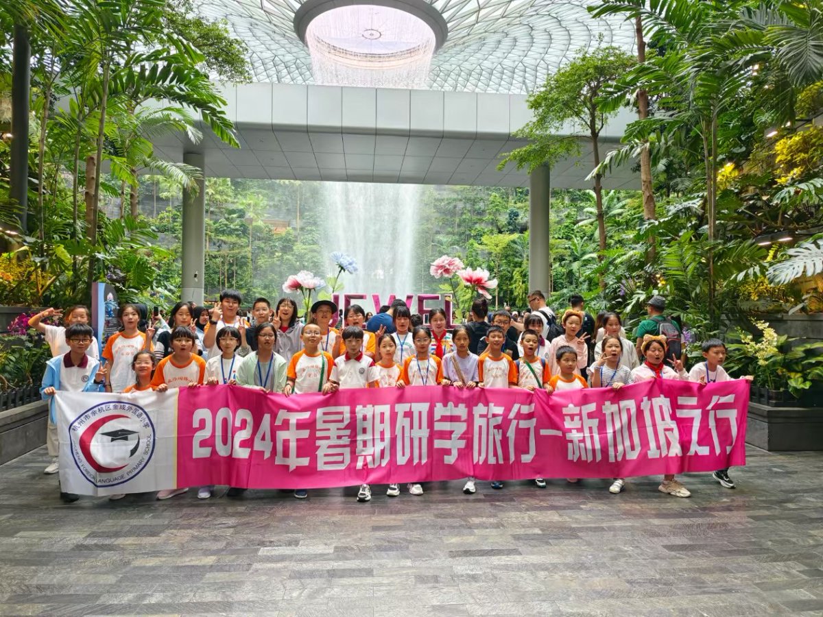 A group of people holding a banner in a botanical-themed indoor garden. The banner reads Summer Research Trip 2024 Singapore.