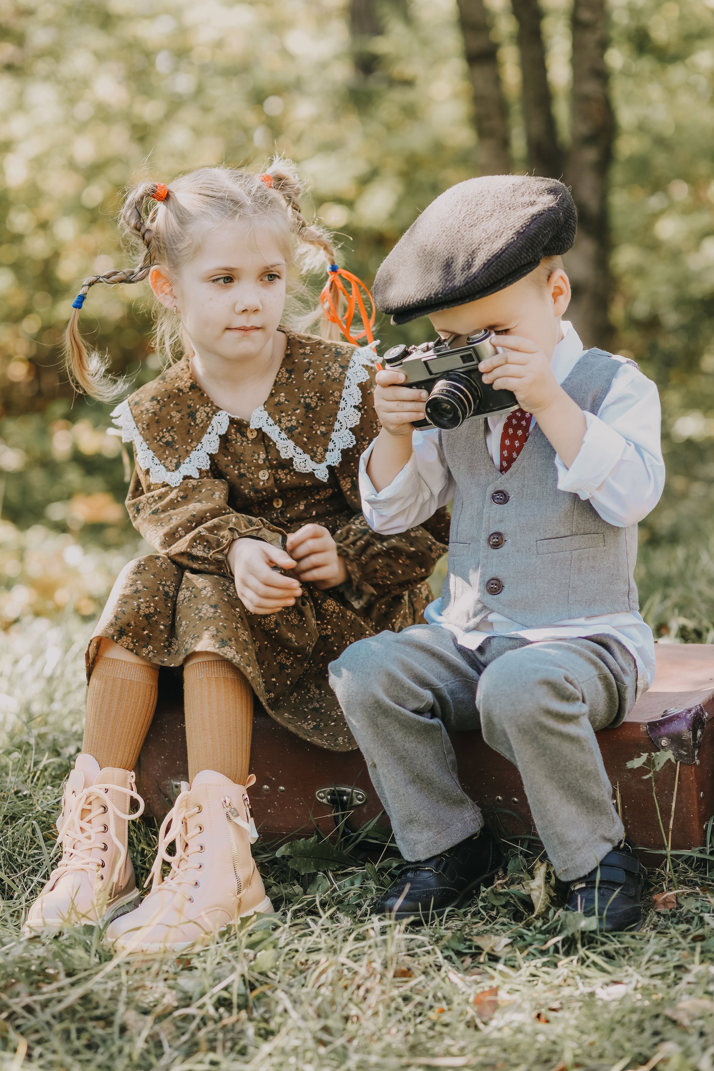 little boy in the park posing with little children boy and girl in the park taking pictures on a retro camera in autumn