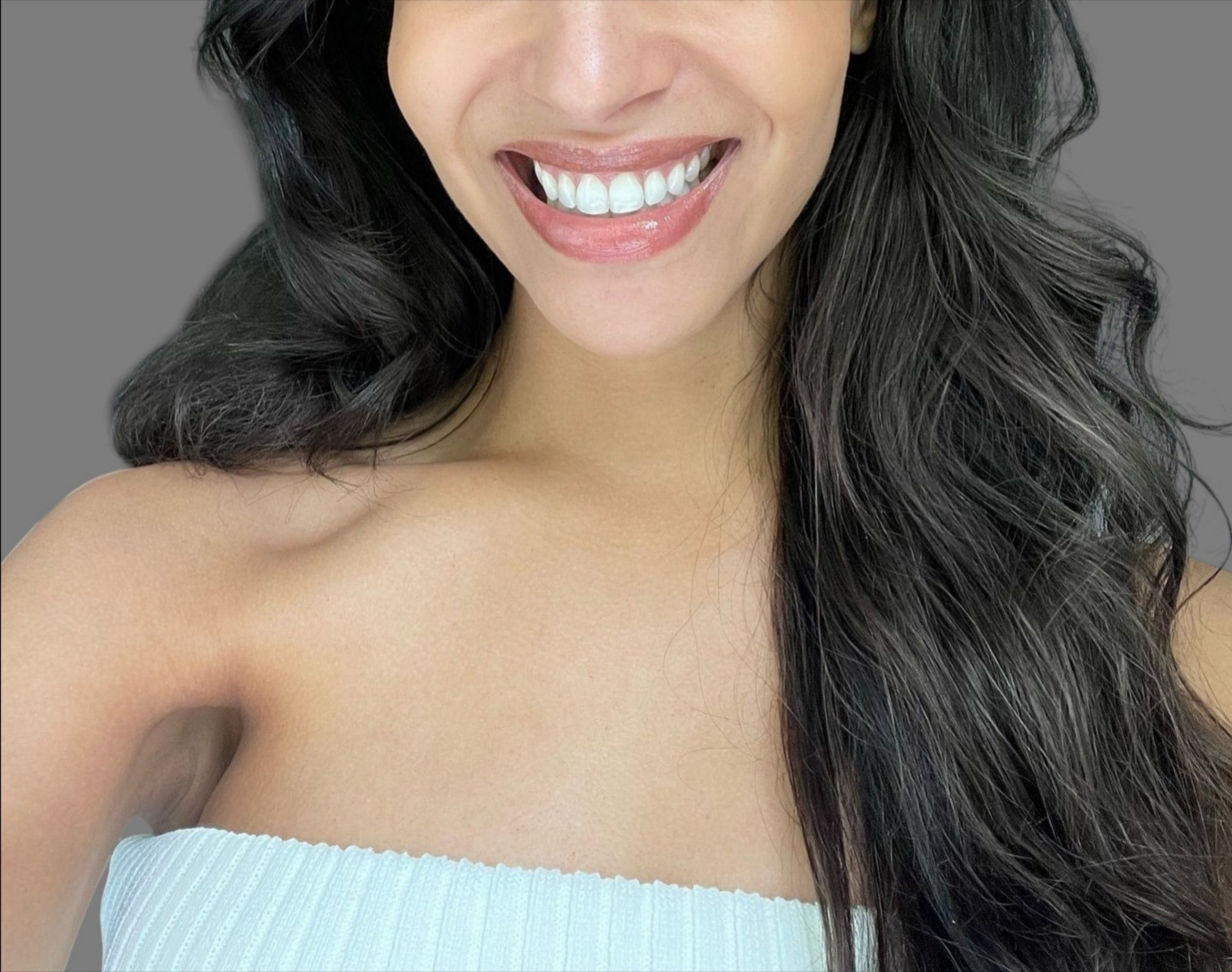 Studio portrait of a young Caucasian woman with flawless, radiant skin, sleek black hair, and refined makeup. Captured in soft lighting, highlighting modern beauty and skincare concepts.
