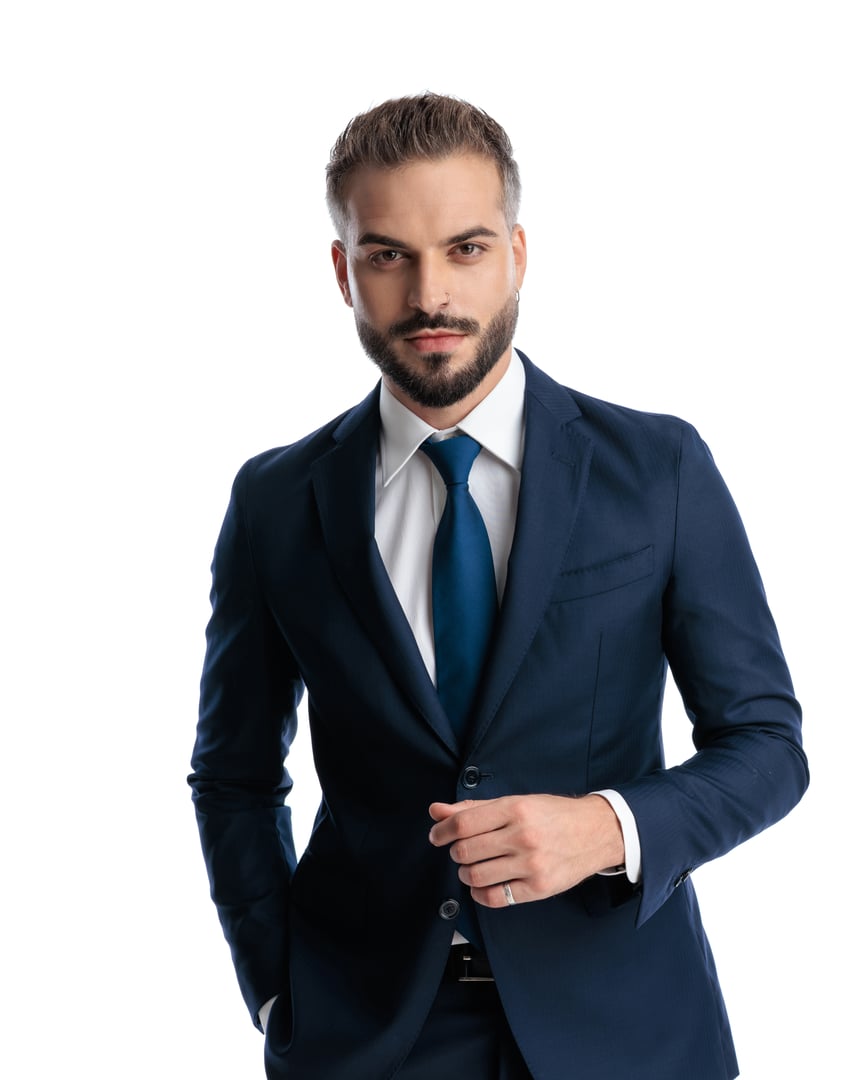 portrait of elegant mature man in navy blue suit holding hand in pocket and posing in a confident way in front of white background