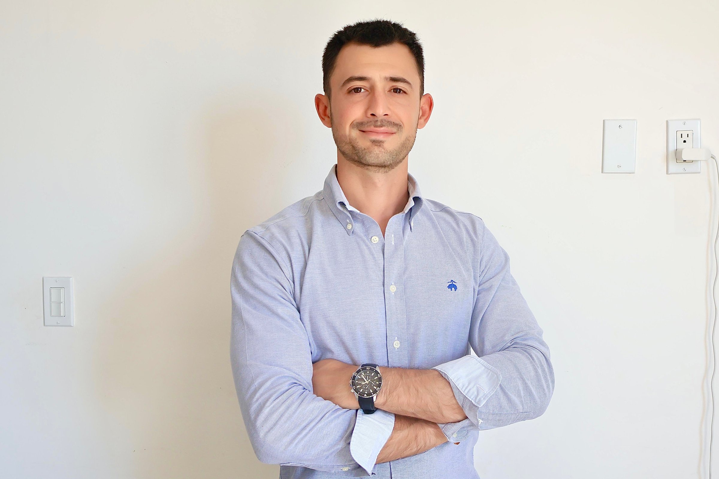 A man standing in a conference room pointing at a screen displaying data while others sit at a table listening.