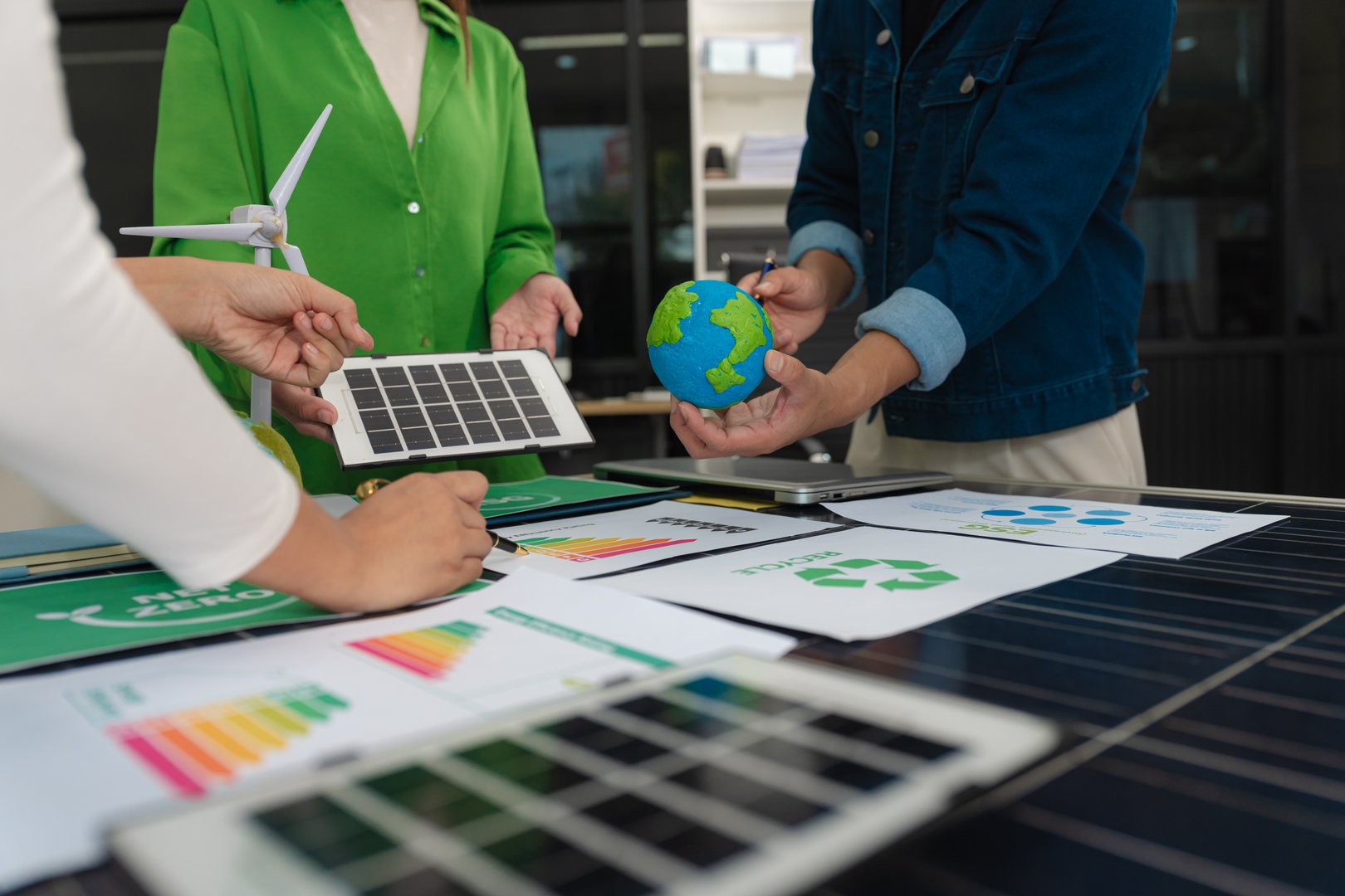 colleagues discussing data working and tablet, laptop with on Construction Site project, green energy and solar panel concept.