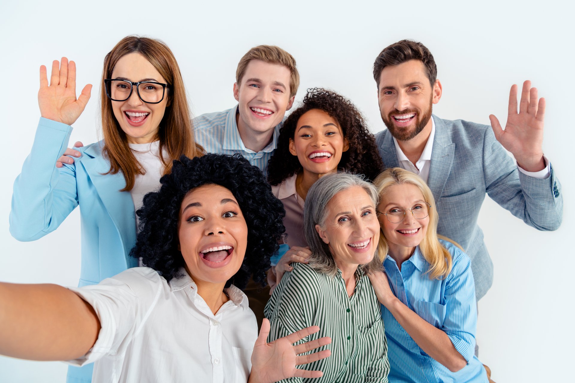 Diverse team of individuals from various professions smiling and interacting in a cheerful and professional setting, showcasing collaboration and teamwork on a light gray background.