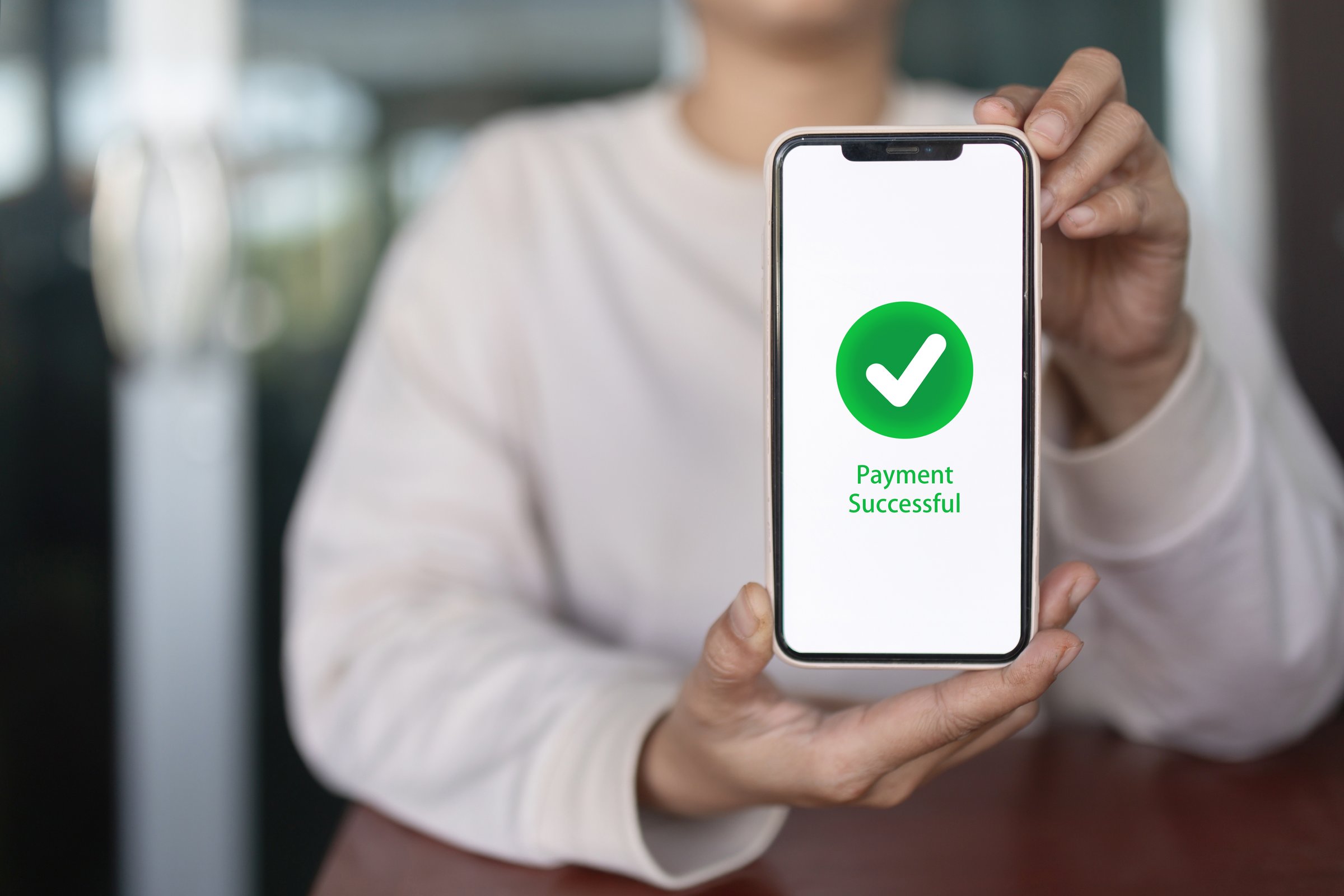 Close-up of person showing smartphone screen with payment successful message