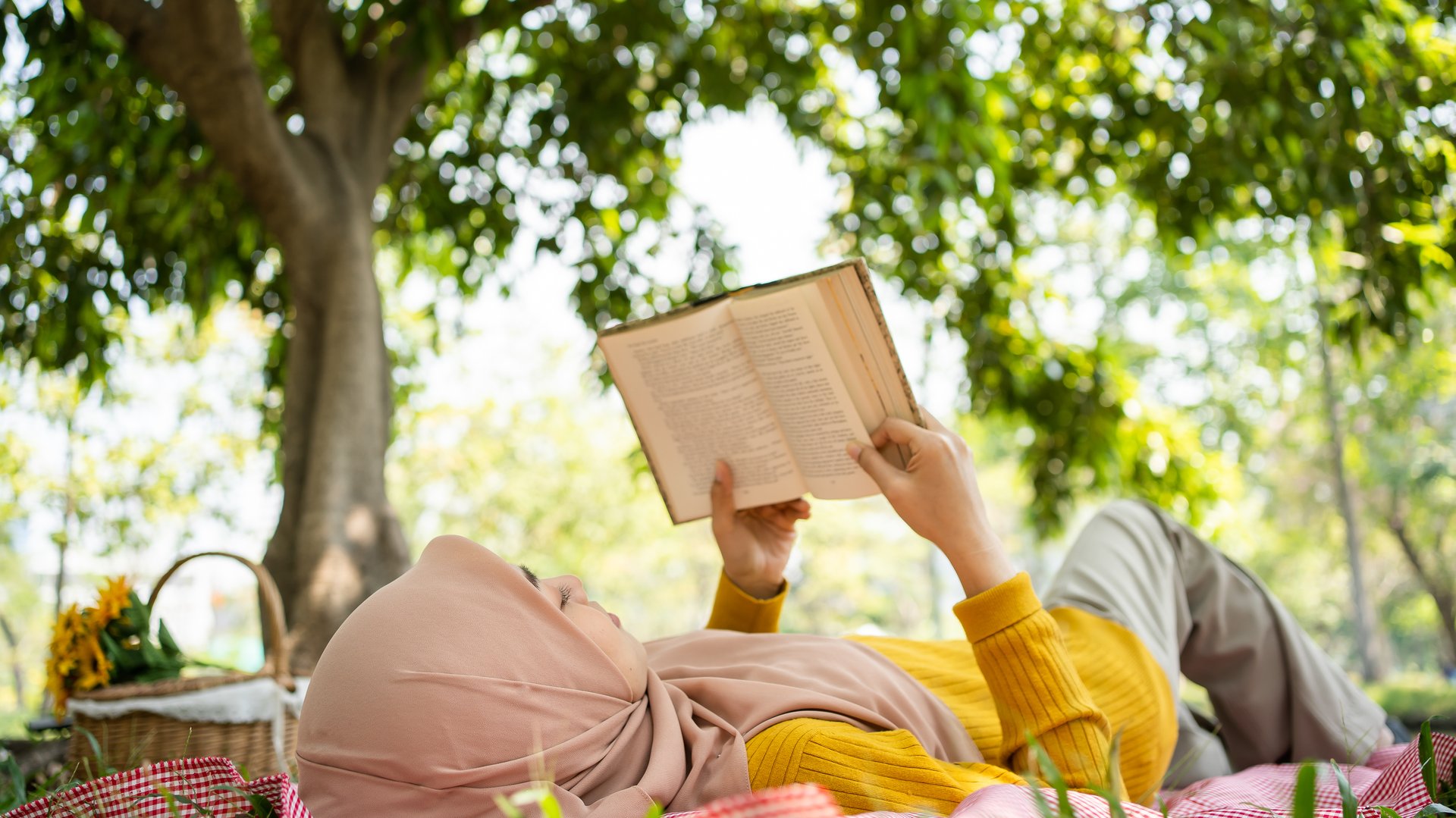 Young Muslim woman reading and enjoying the fresh air in a green forest. Enjoying the nature.