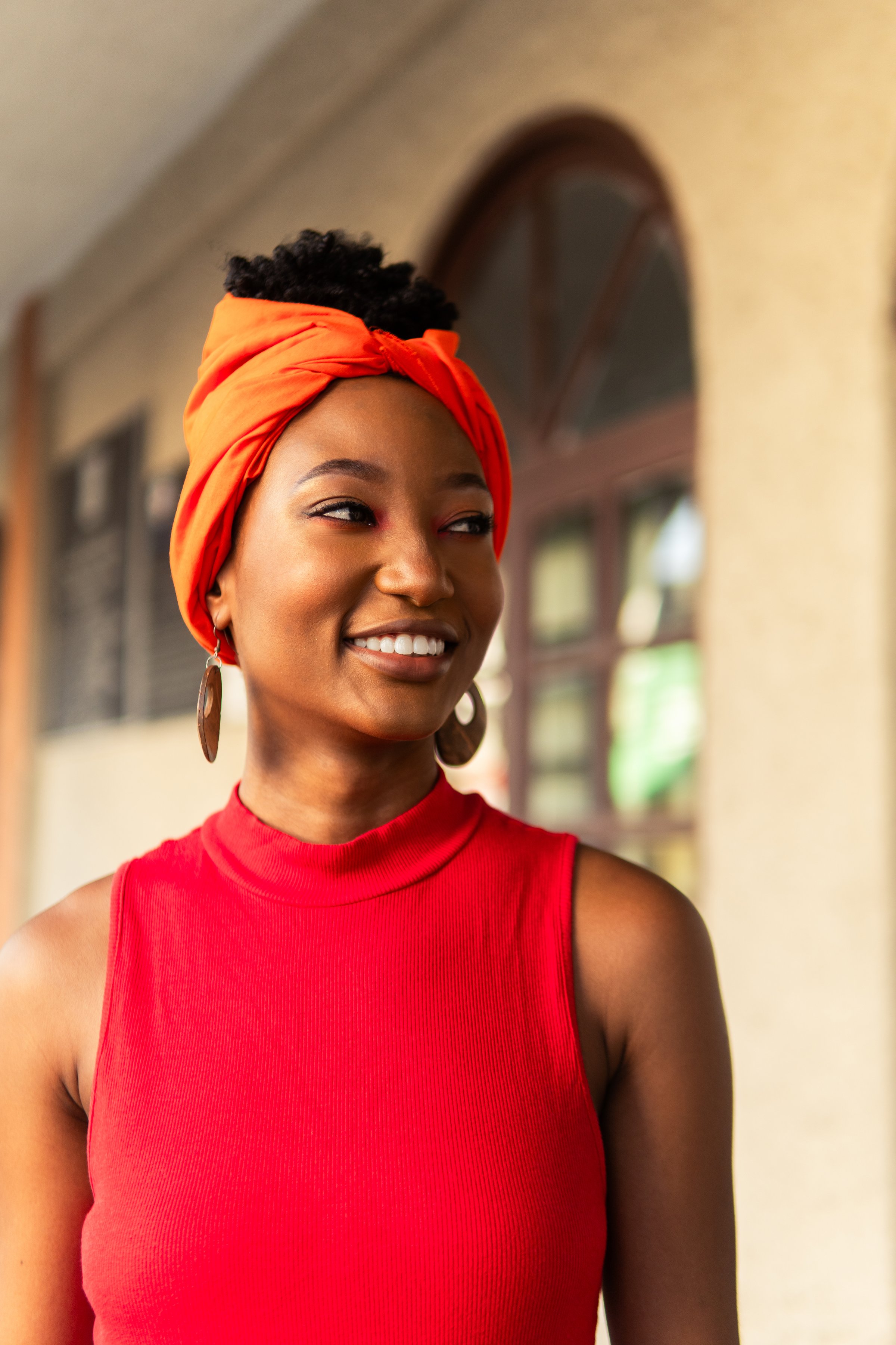 Portrait of a young garifuna woman smiling and wearing a bright orange turban