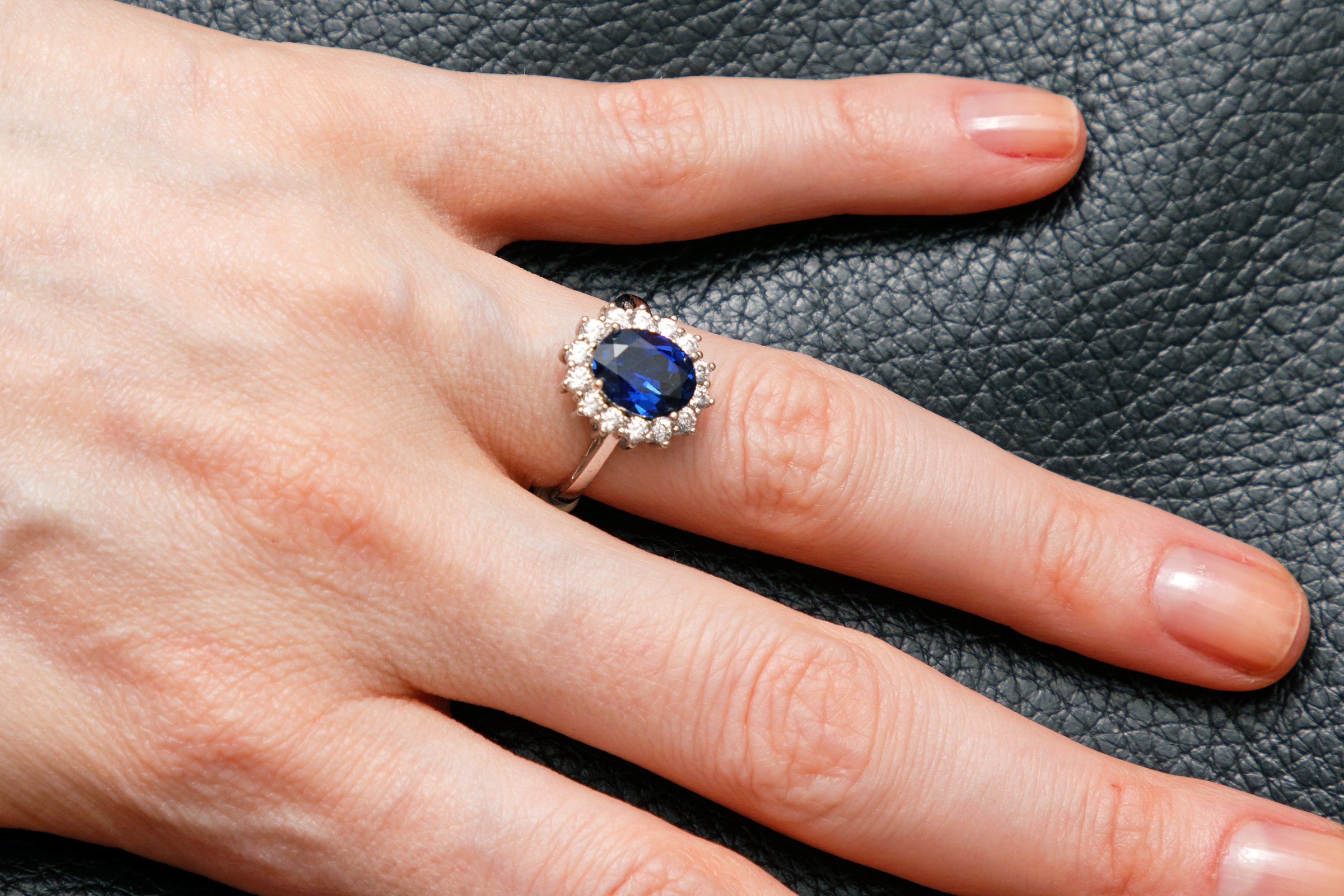 Large oval blue sapphire ring with diamonds on female hand